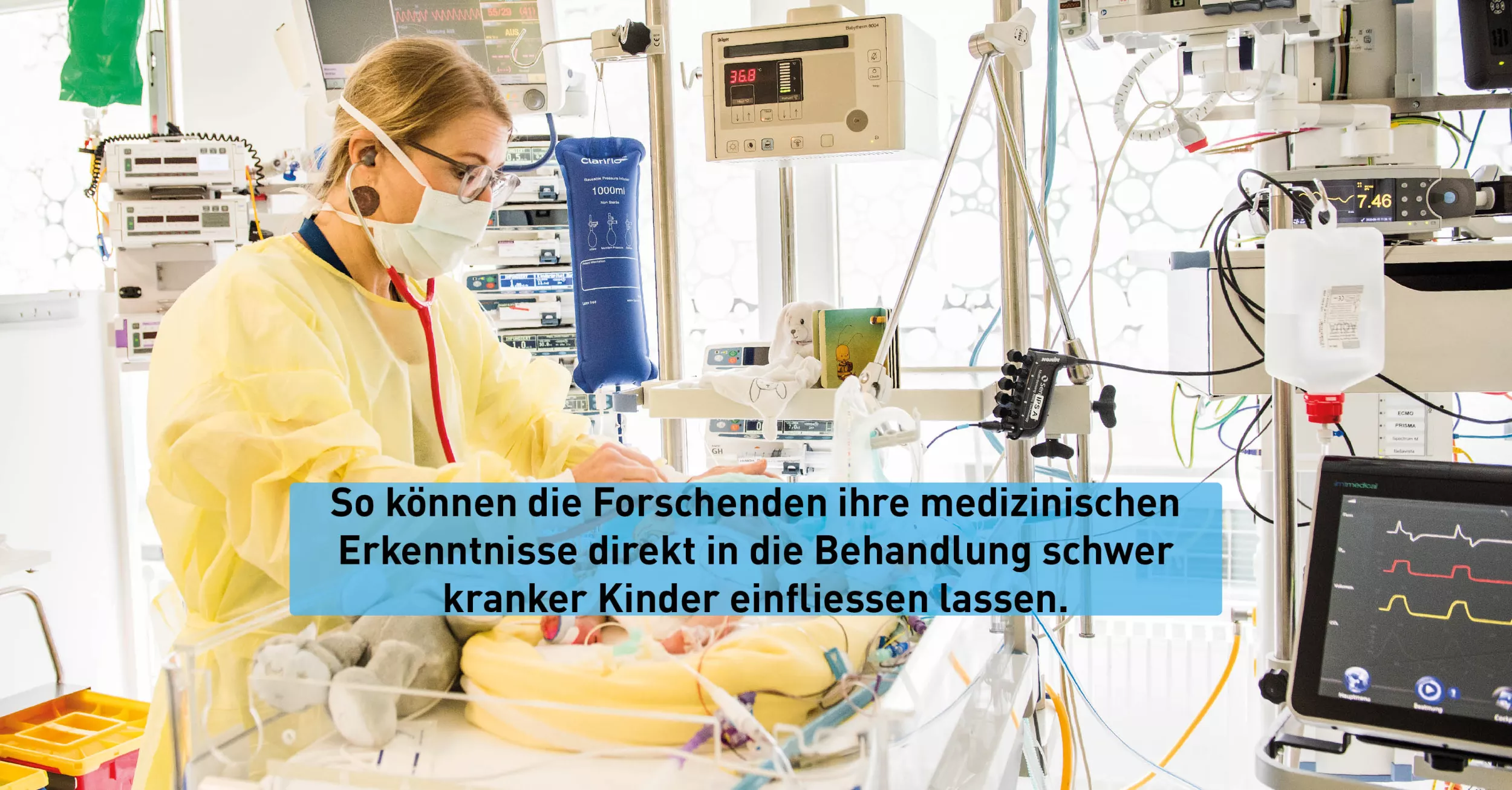 Eine blonde Frau mit Brille und Maske steht vor einem Bett in dem sich ein Baby befindet. Um sie herum sind verschiedene medizinische Geräte zu sehen. 