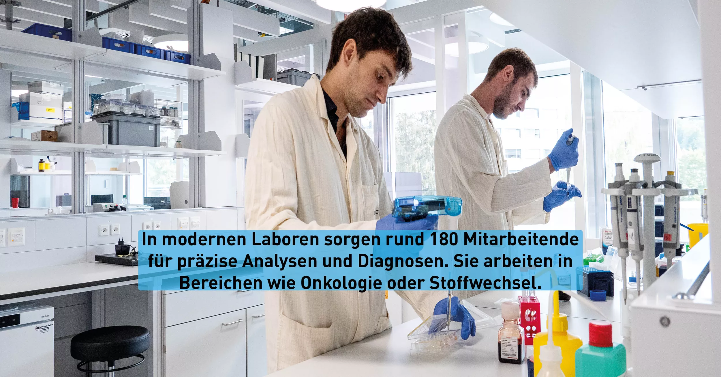 Zwei Forschende in weissen Kitteln stehen in einem Labor und untersuchen Proben.