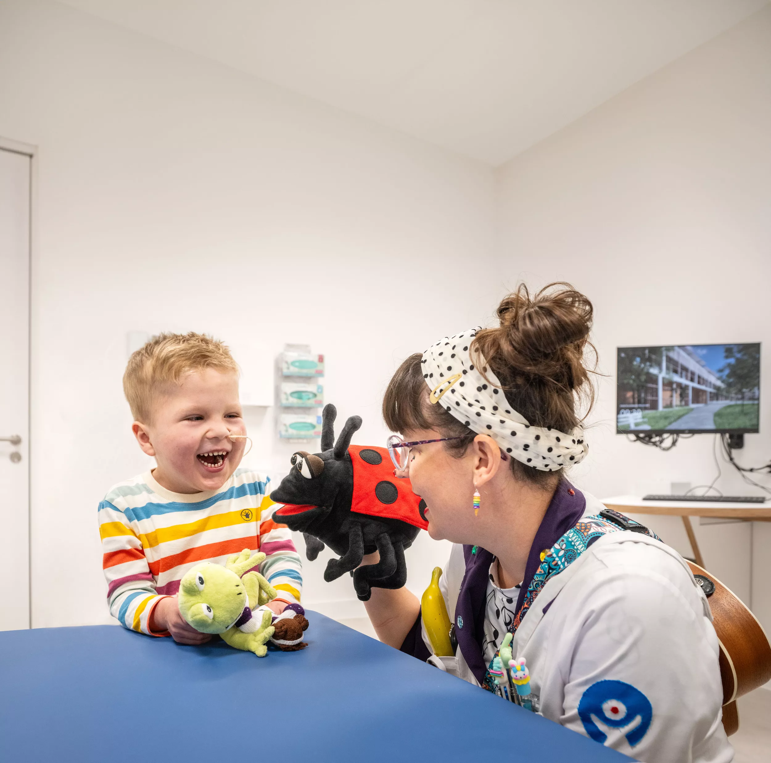 Spitalclownin ChaChaCha und Patient Frederik spielen mit Plüschtieren