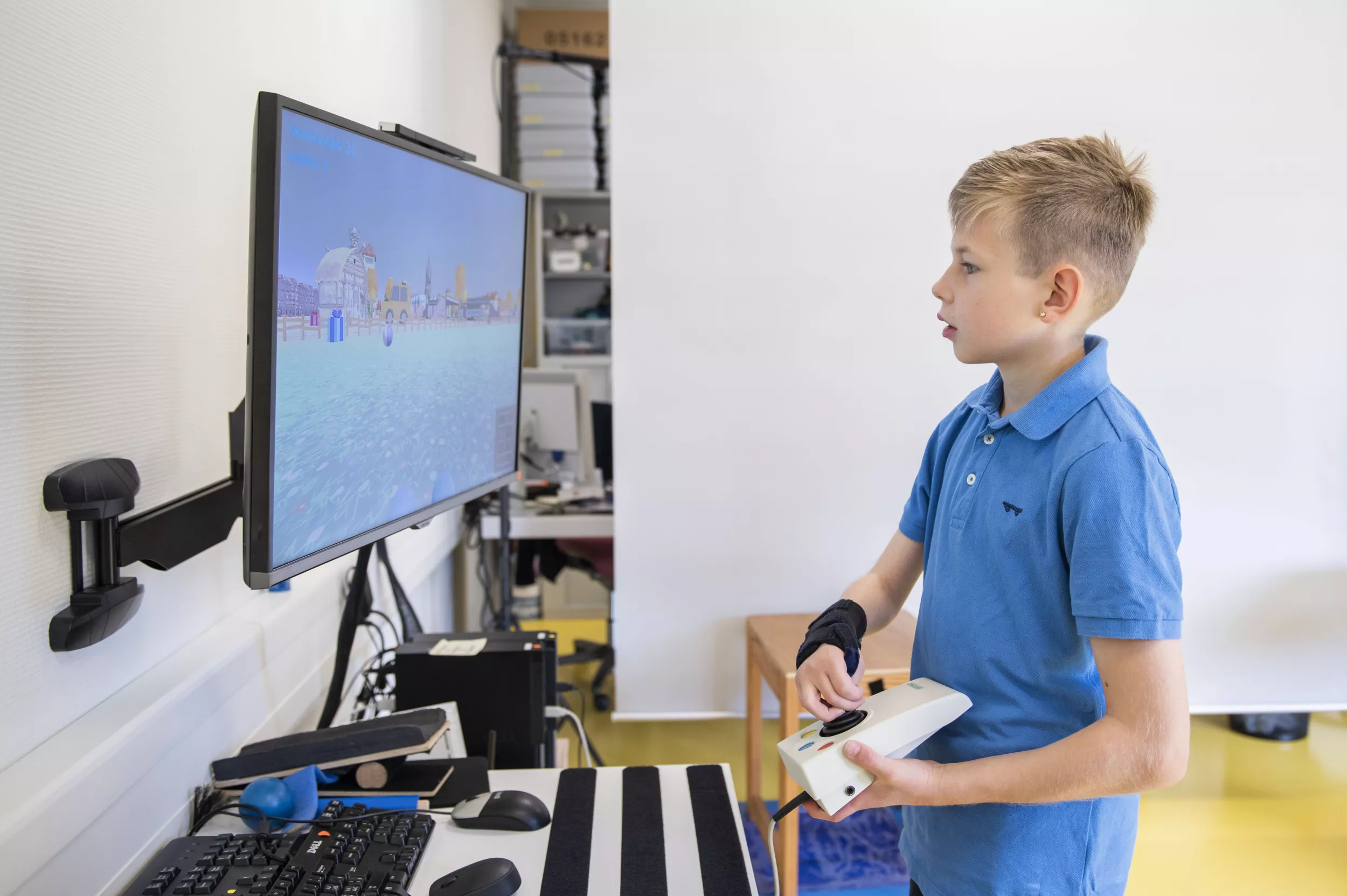 Ein junger Reha-Patient spielt ein Computerspiel mit Controller