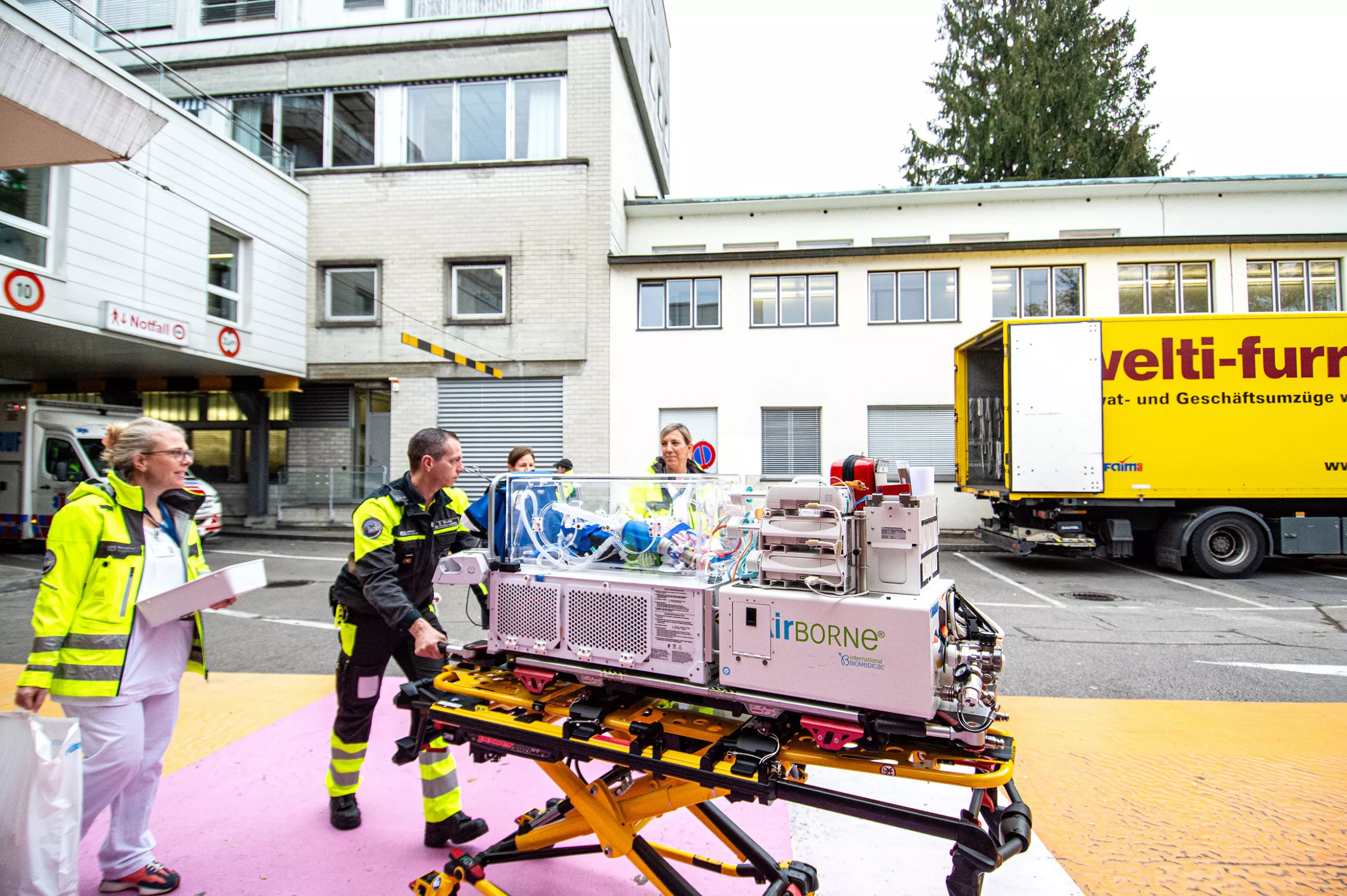 Rettungssanitäter und medizinische Fachpersonen schieben ein Baby auf einer Transportliege aus dem Kinderspital in Zürich-Hottingen