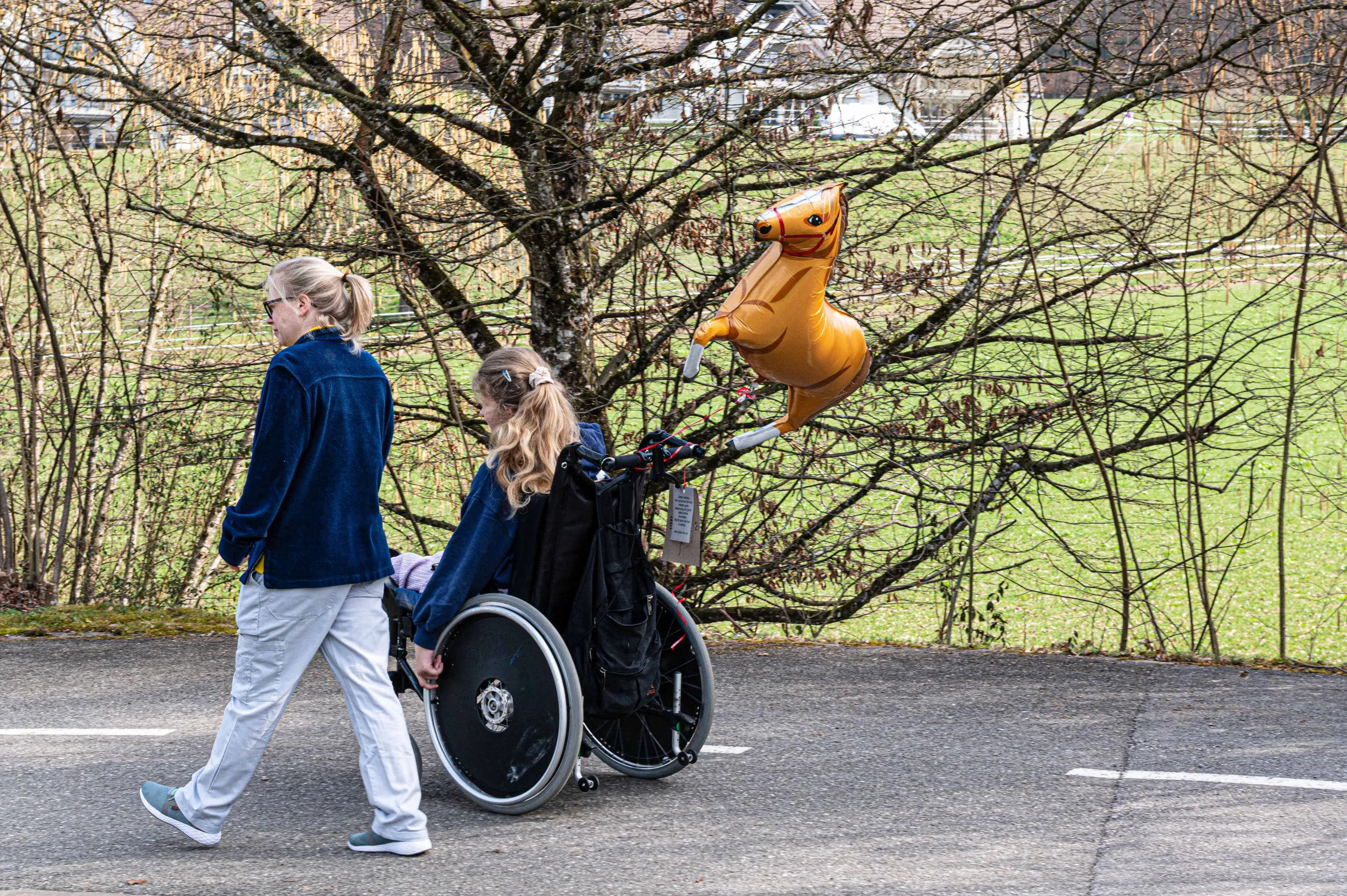 Eine Therapeutin und ein Kind im Rollstuhl fahren im Freien