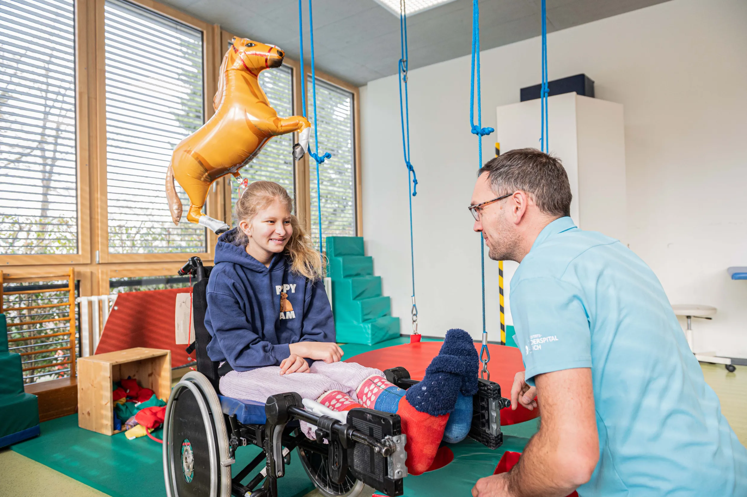 Ein Therapeut und ein junges Mädchen im Rollstuhl in der Kinder-Reha Schweiz