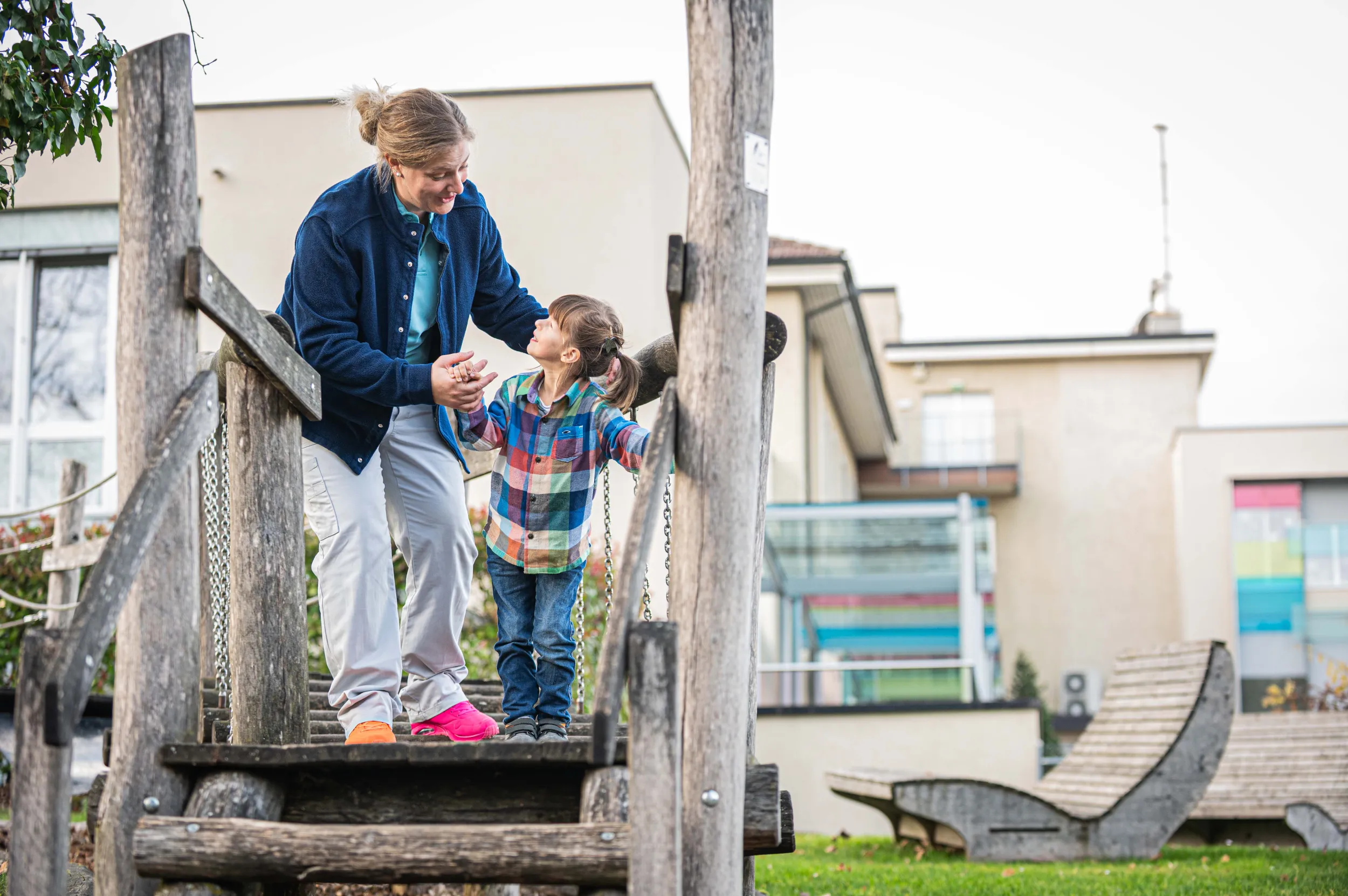 Eine Therapeutin und ein jungens Kind auf dem Spielplatz vor der Kinder-Reha Schweiz