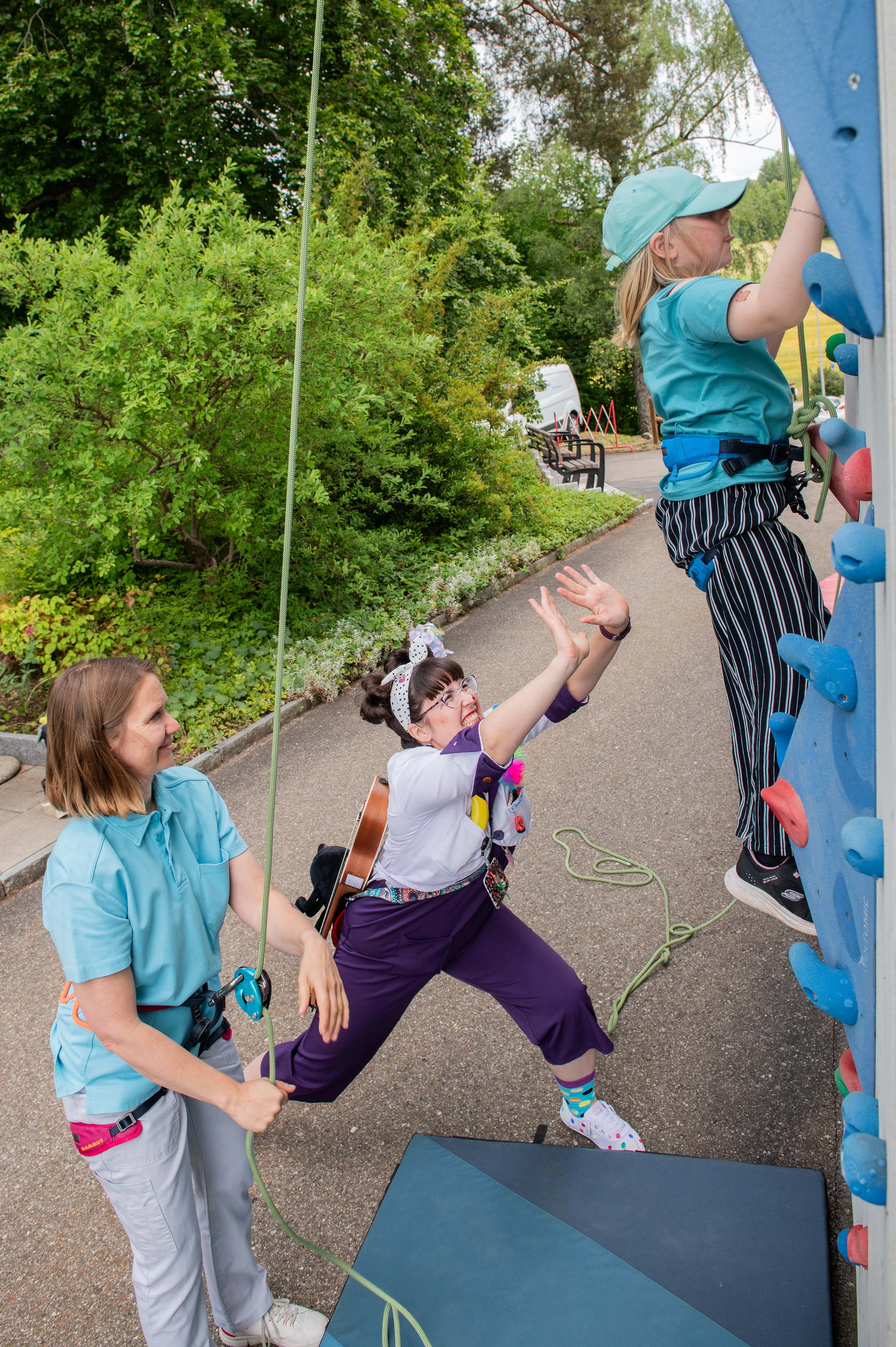 Ein Kind, eine Therapeutin und eine Spitalclownin an der Kletterwand in der Kinder-Reha Schweiz