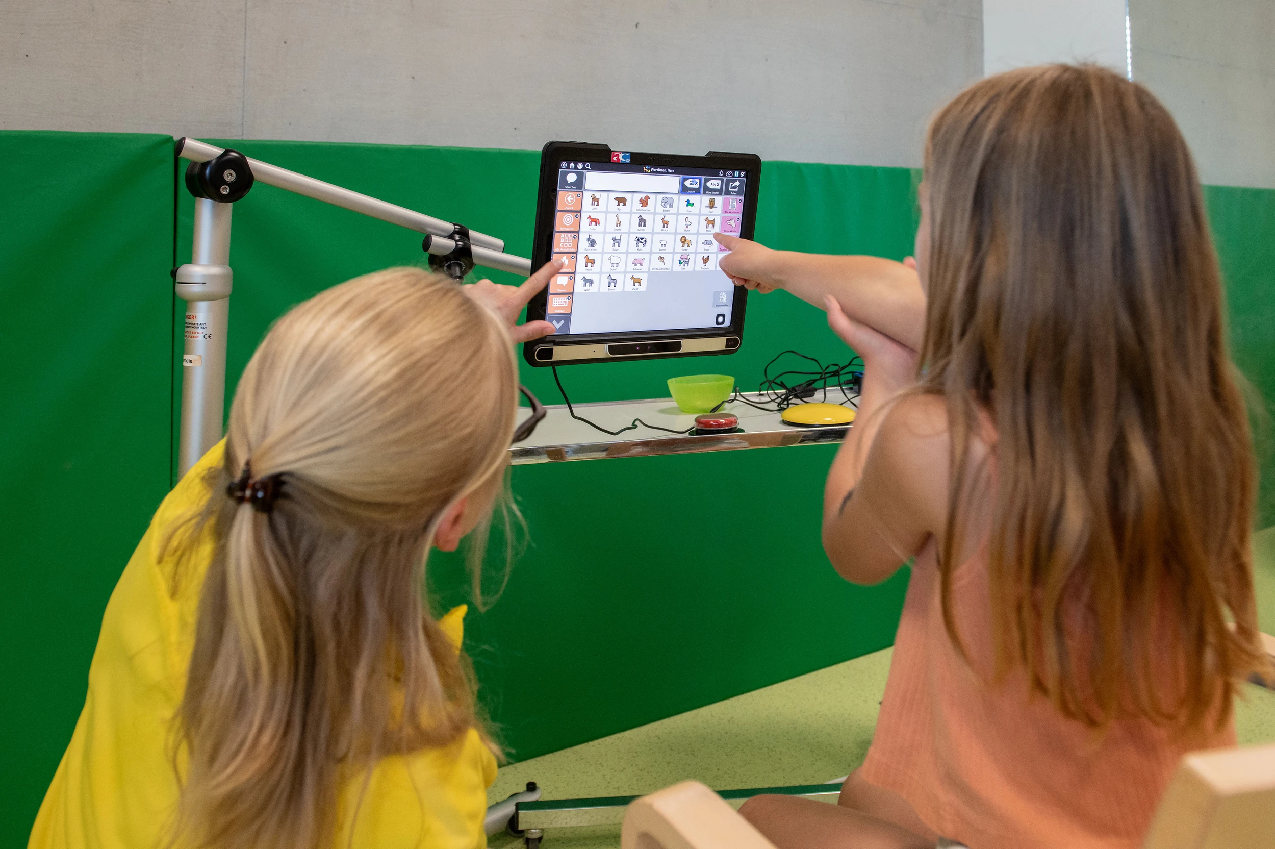 Eine Therapeutin erklärt einem Kind unterstützte Kommunikation an einem Tablet in der Kinder-Reha Schweiz