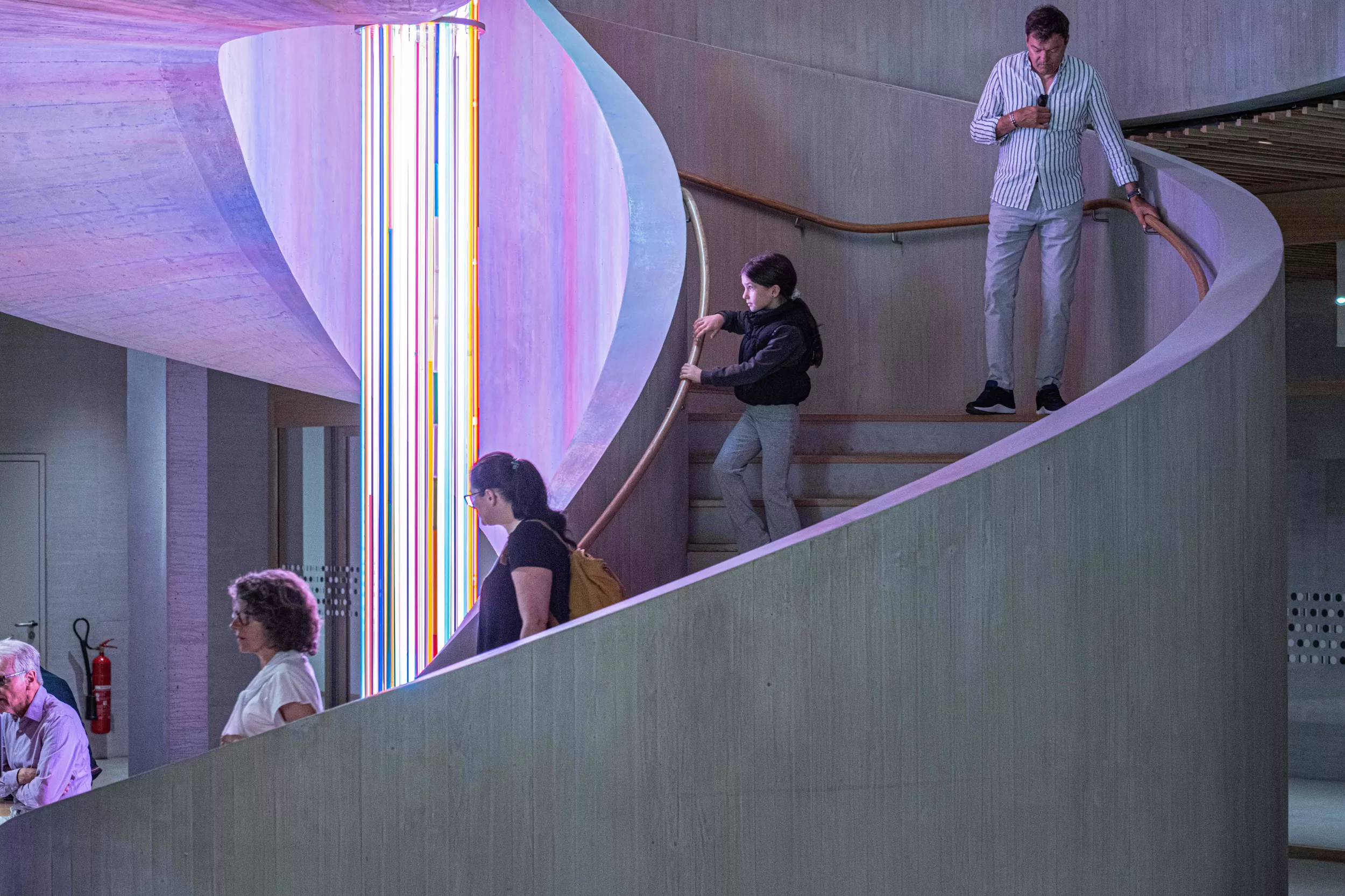 Besuchende auf der Rundtreppe mit Kunstbeleuchung von Raphael Hefti