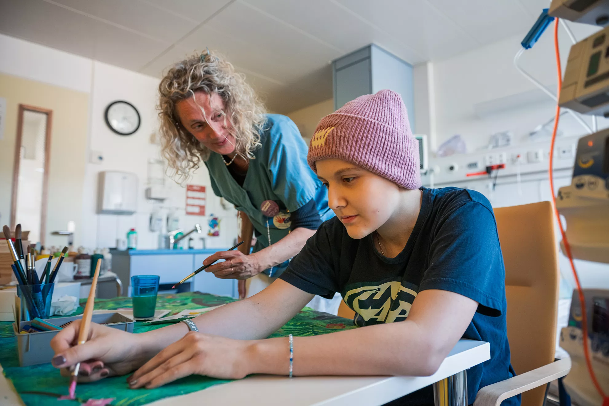 Eine junge Patientin und Kunsttherapeutin malen mit Wasserfarben