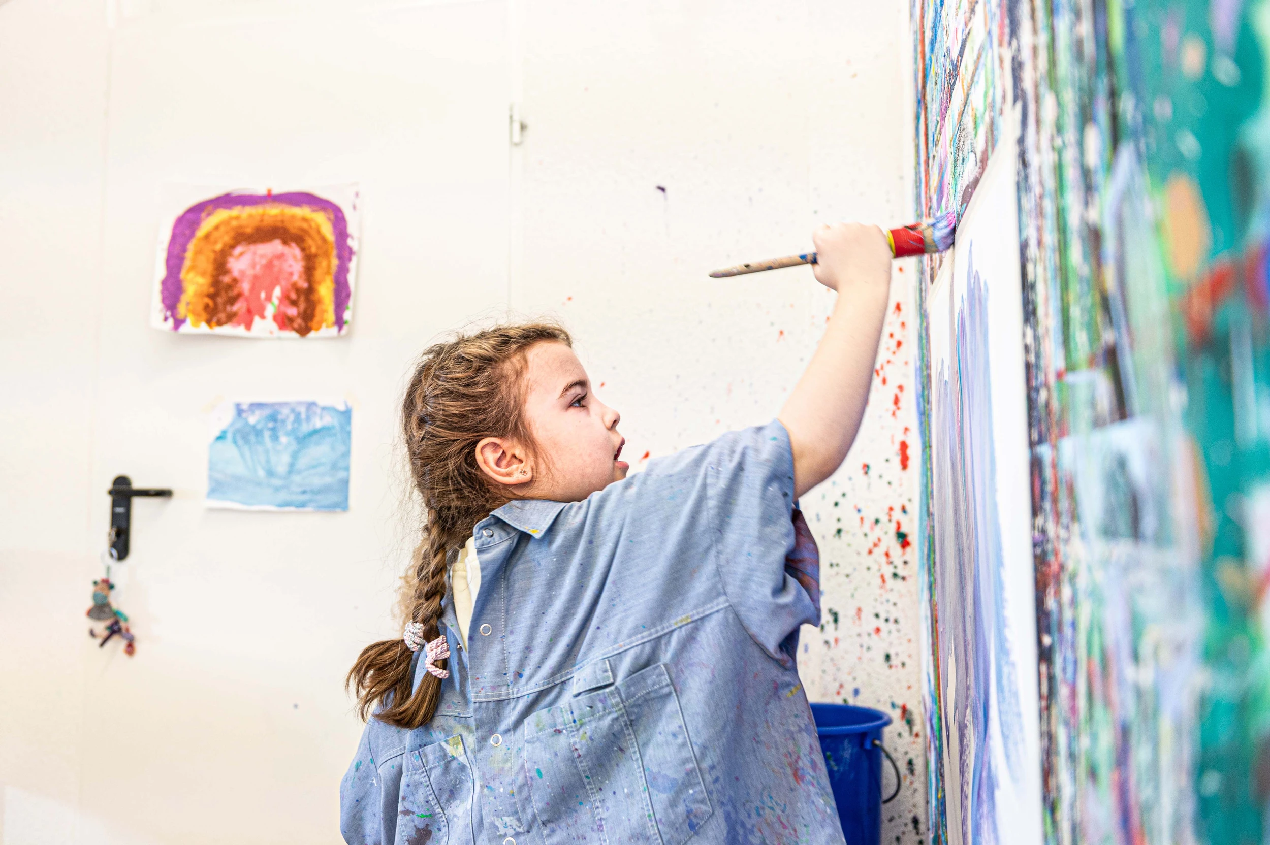 Patientin Vivian in der Kinder-Reha Schweiz malt mit einem Pinsel auf einer Leinwand.