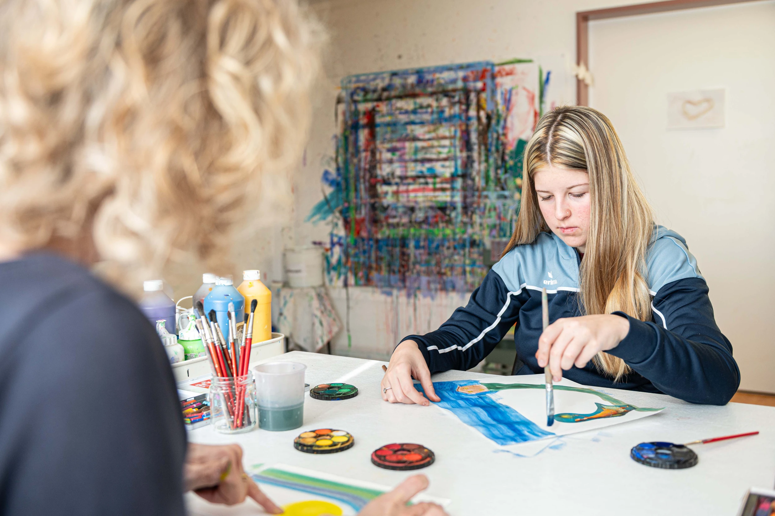 Patientin Joelle in der Kinder-Reha Schweiz malt zusammen mit einer Kunsttherapeutin Bilder.