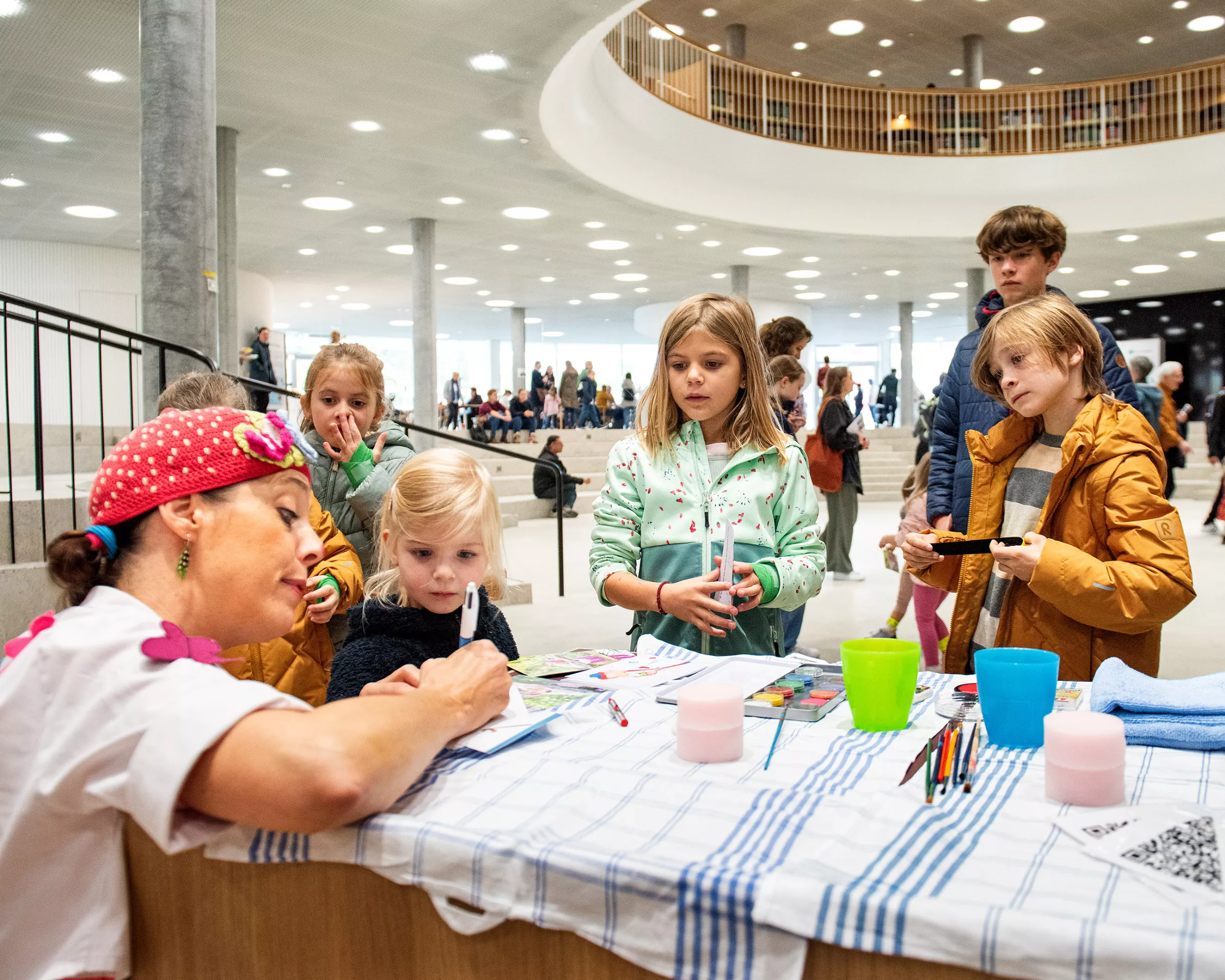Eine als Clown verkleidete Frau schminkt Kinder.