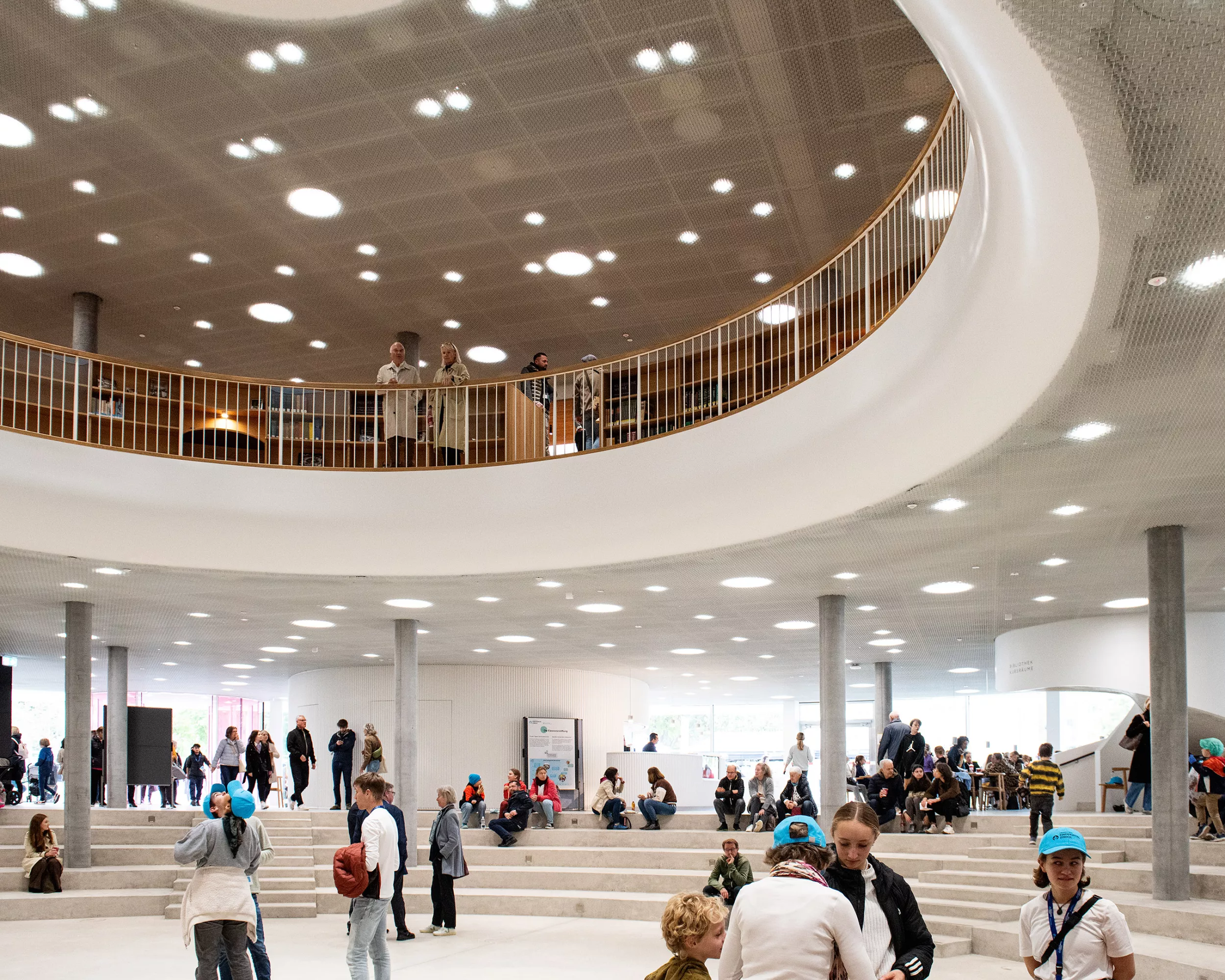 Erwachsene und Kinder besichtigen das Foyer und die Bibliothek im Gebäude für Forschung und Lehre