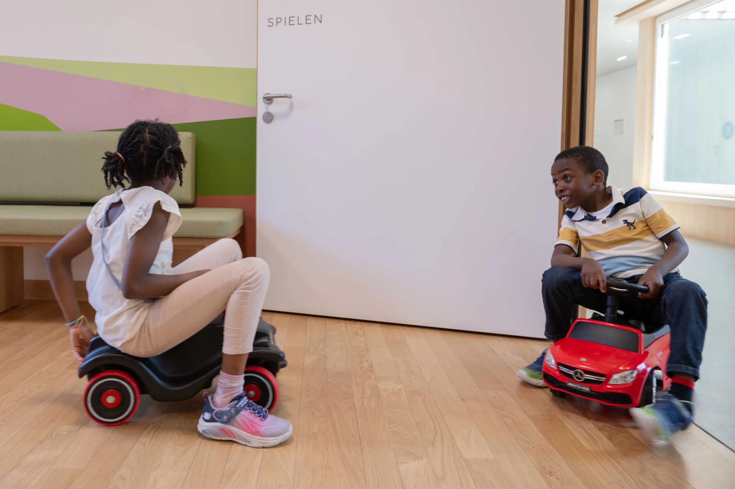 Patient David fährt Bobbycar mit seiner Schwester im Kinderspital Zürich