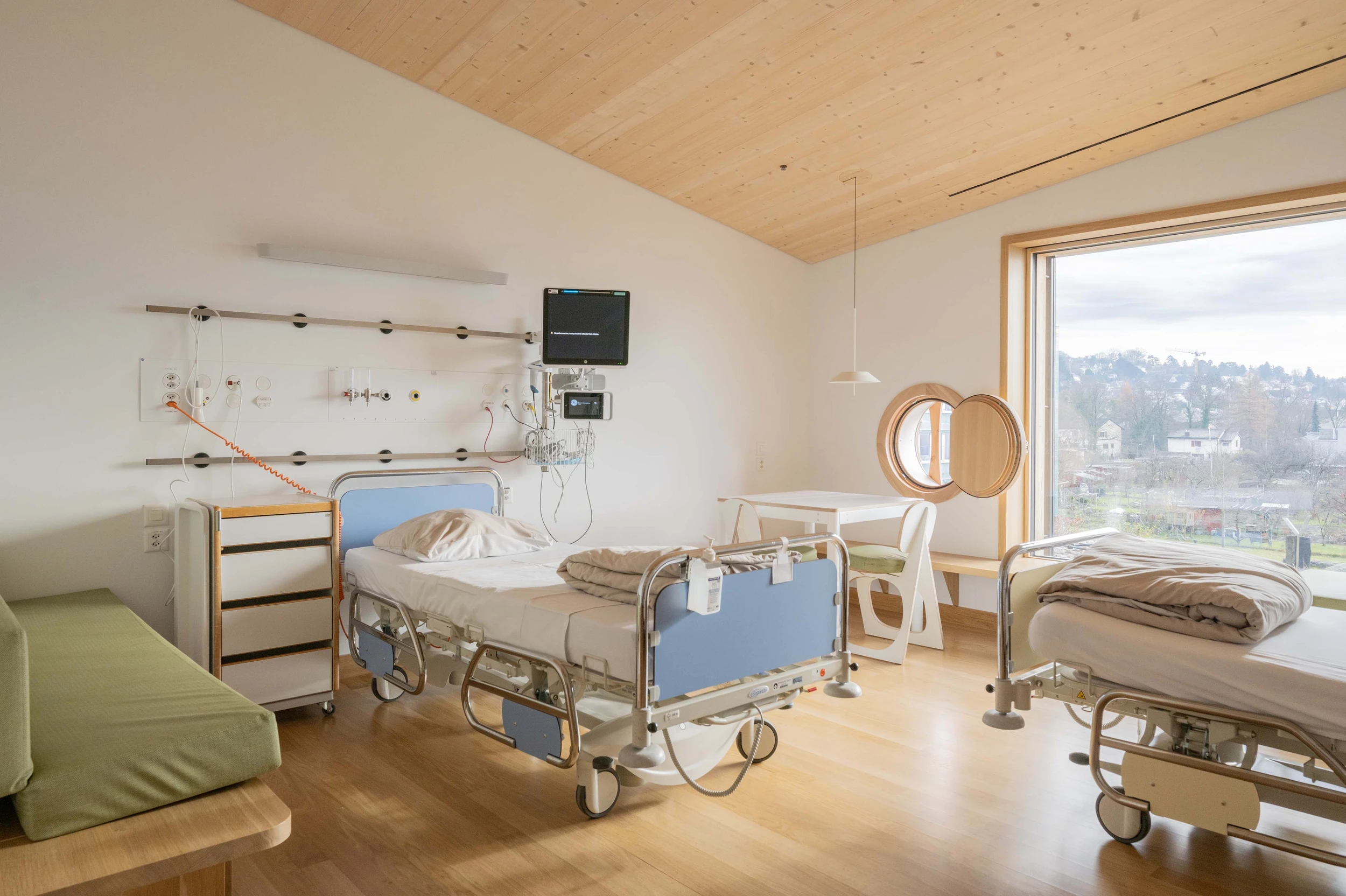Ein Zweibett-Patientenzimmer mit ausziehbareren Liegebänken für ein je ein übernachtendes Familienmitglied