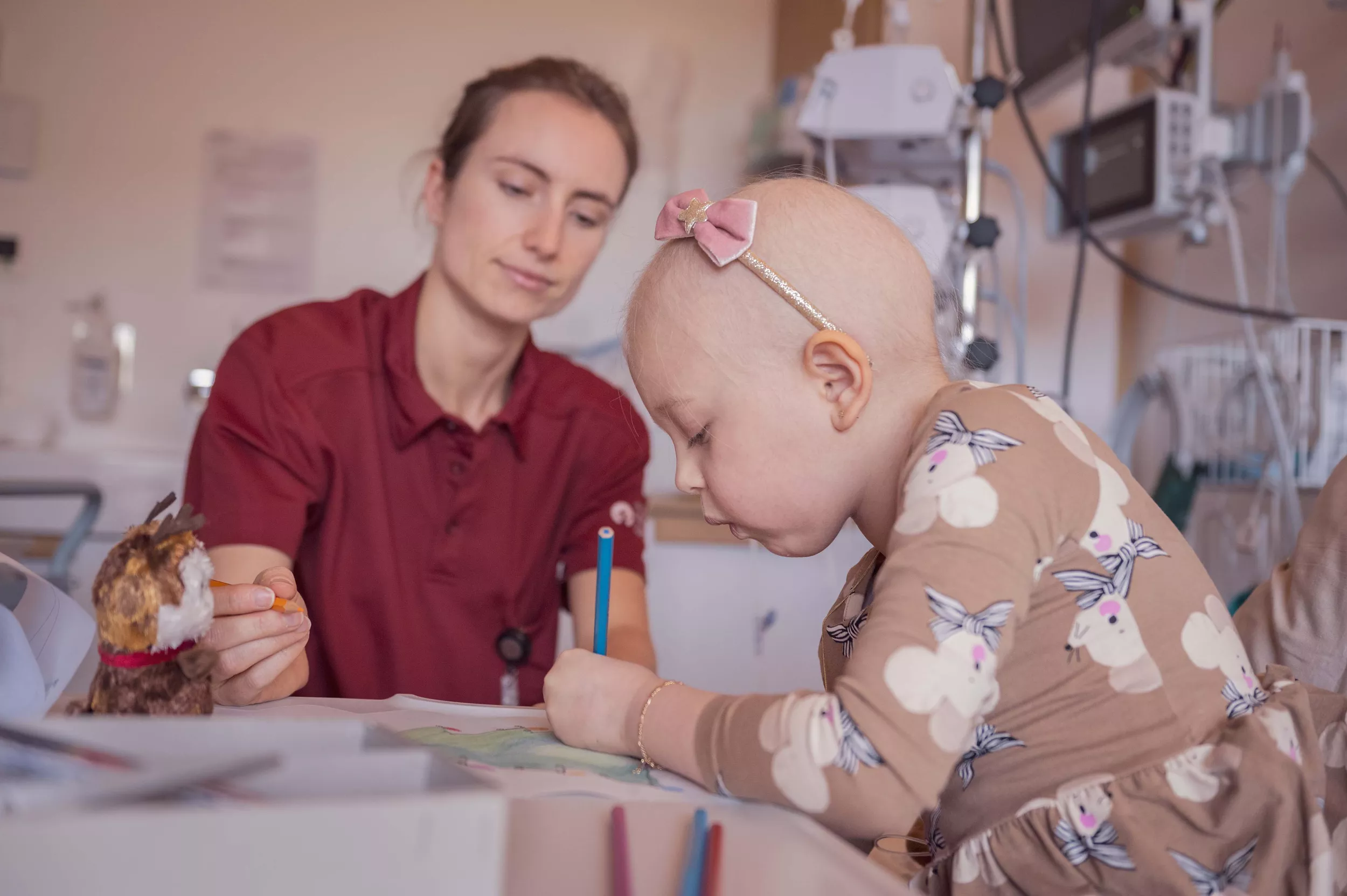 Eine junge Onkologie-Patientin malt ein Bild zusammen mit einer Lehrerin der Spitalschule