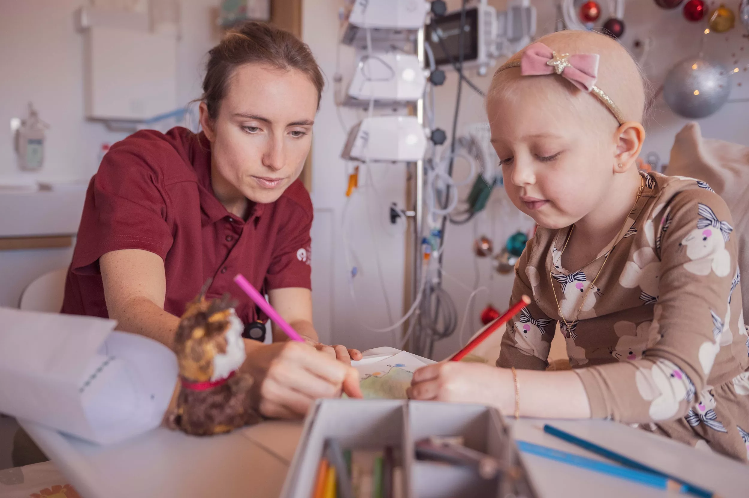 Eine junge Onkologie-Patientin malt ein Bild zusammen mit einer Spitallehrerin