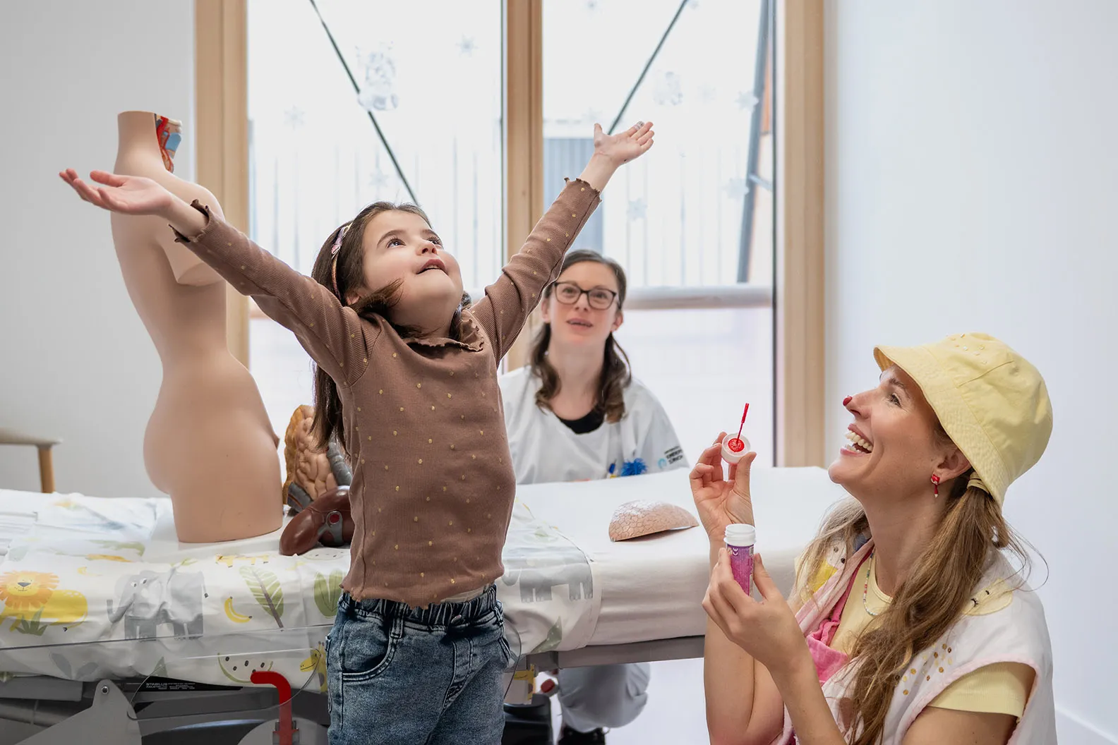 Nephrologie-Patientin Naila springt freudig durchs Spitalzimmer und jagt Luftblasen von der Spitalclownin Lumi.