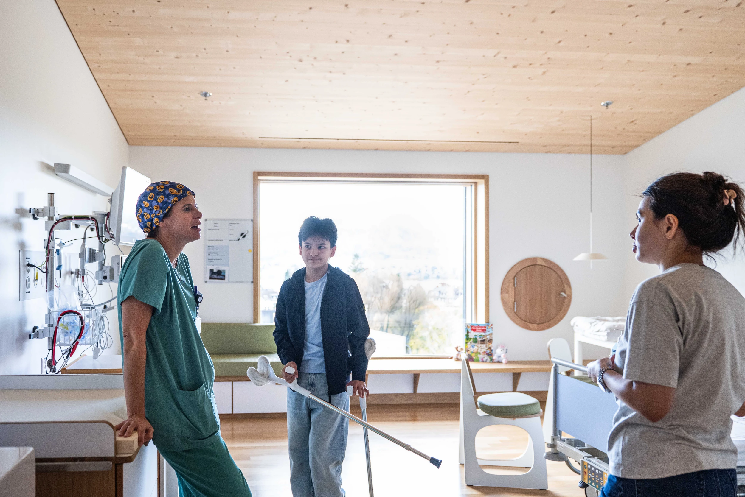 Ein Patient, seine Mutter und eine Ärztin unterhalten sich in einem Patientenzimmer im Kinderspital Zürich