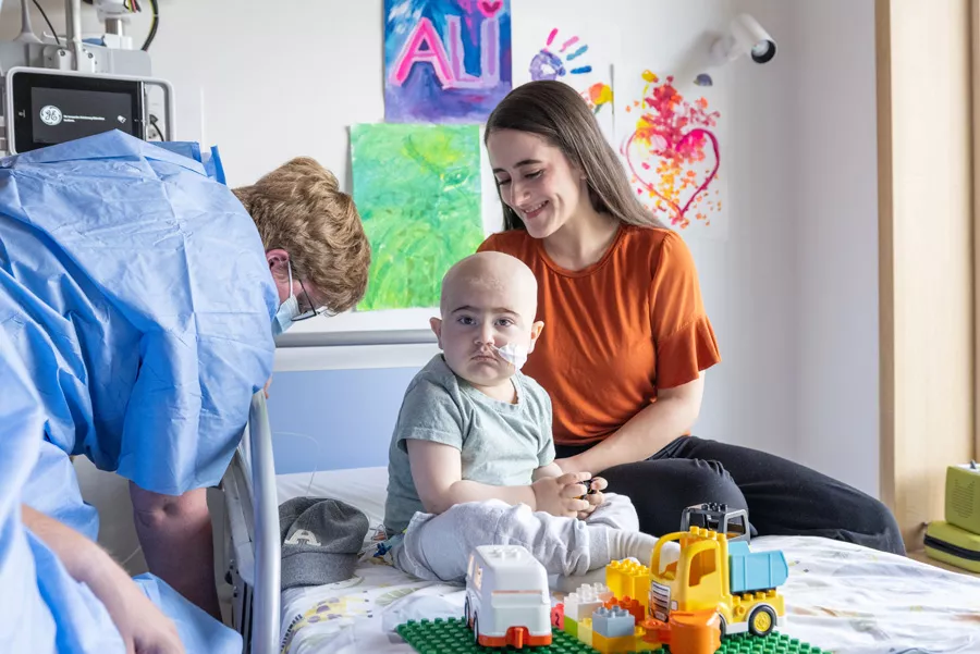 Ali sitzt auf dem Bett mit seiner Mama