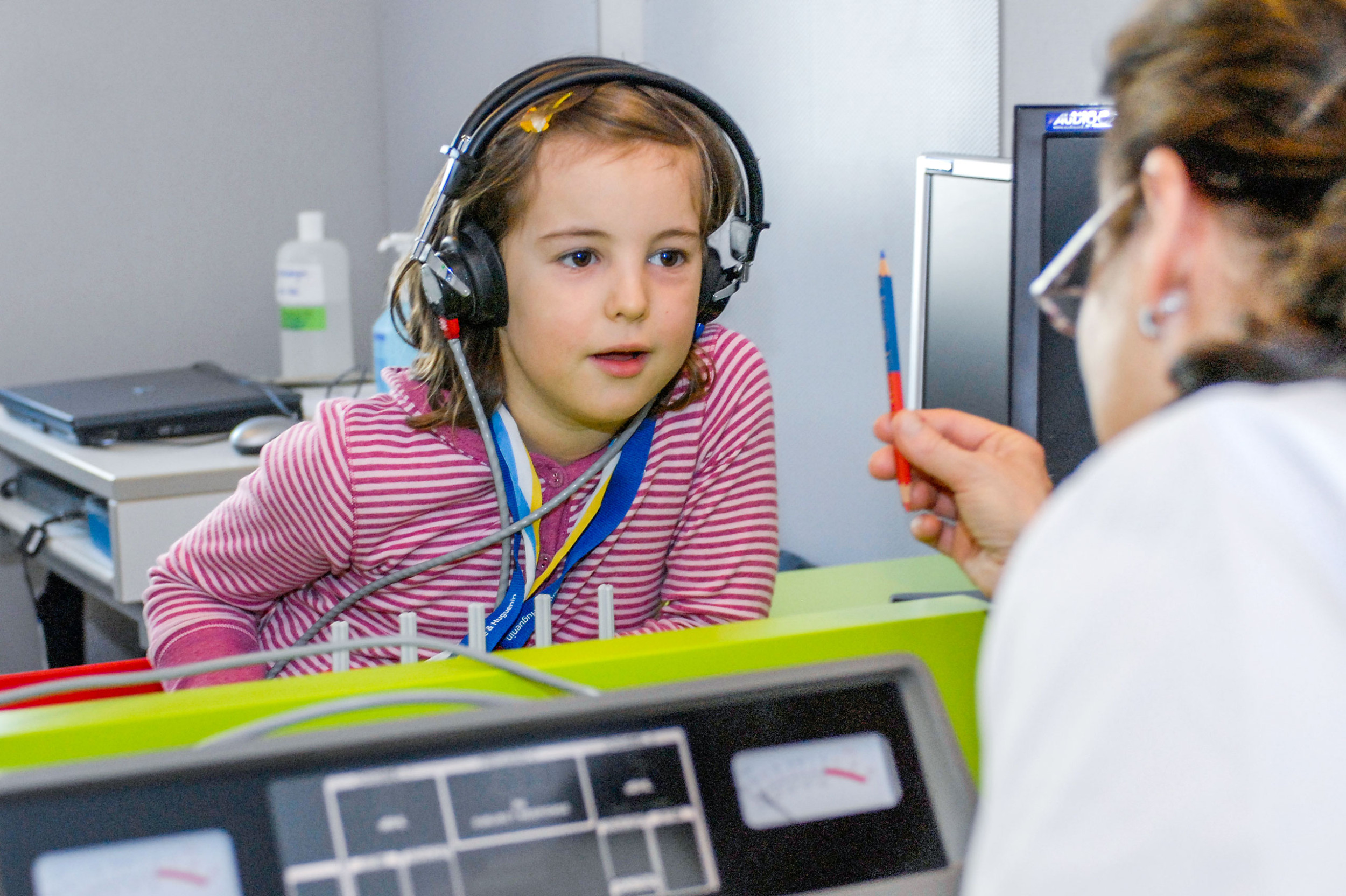 ORL, Audiolabor, Mädchen mit Kopfhörer hört aufmerksam der Akustikerin zu