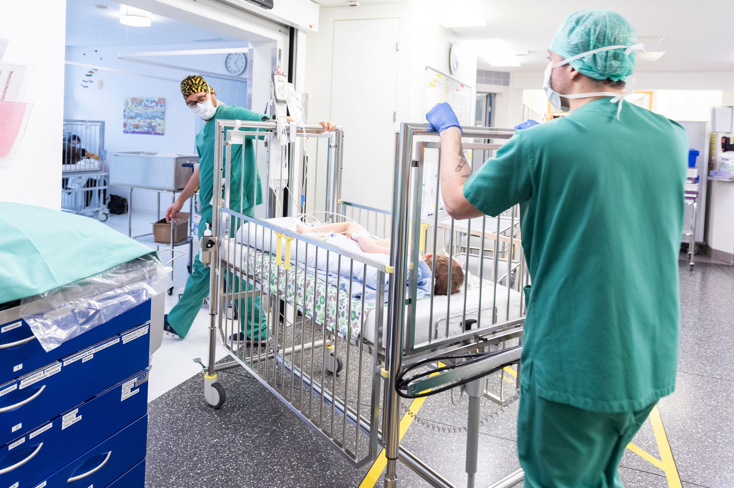 Zwei Anästhesisten bringen ein Kind im Bett nach einer Operation in die Aufwachstation