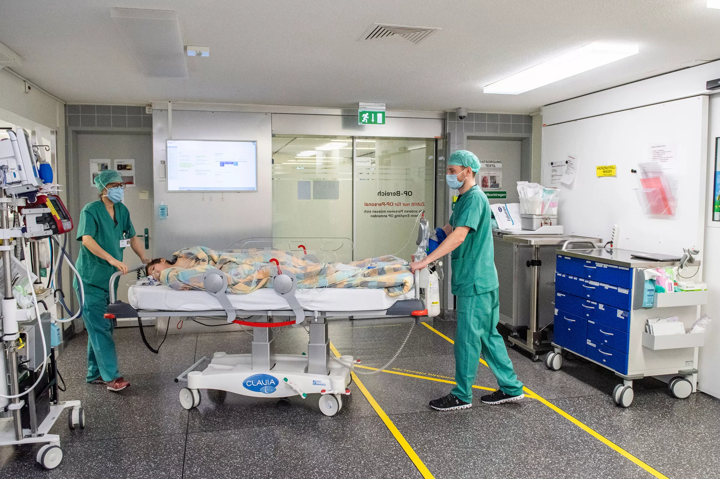 Zwei Anästhesisten bringen ein Kind im Bett nach einer Operation in die Aufwachstation