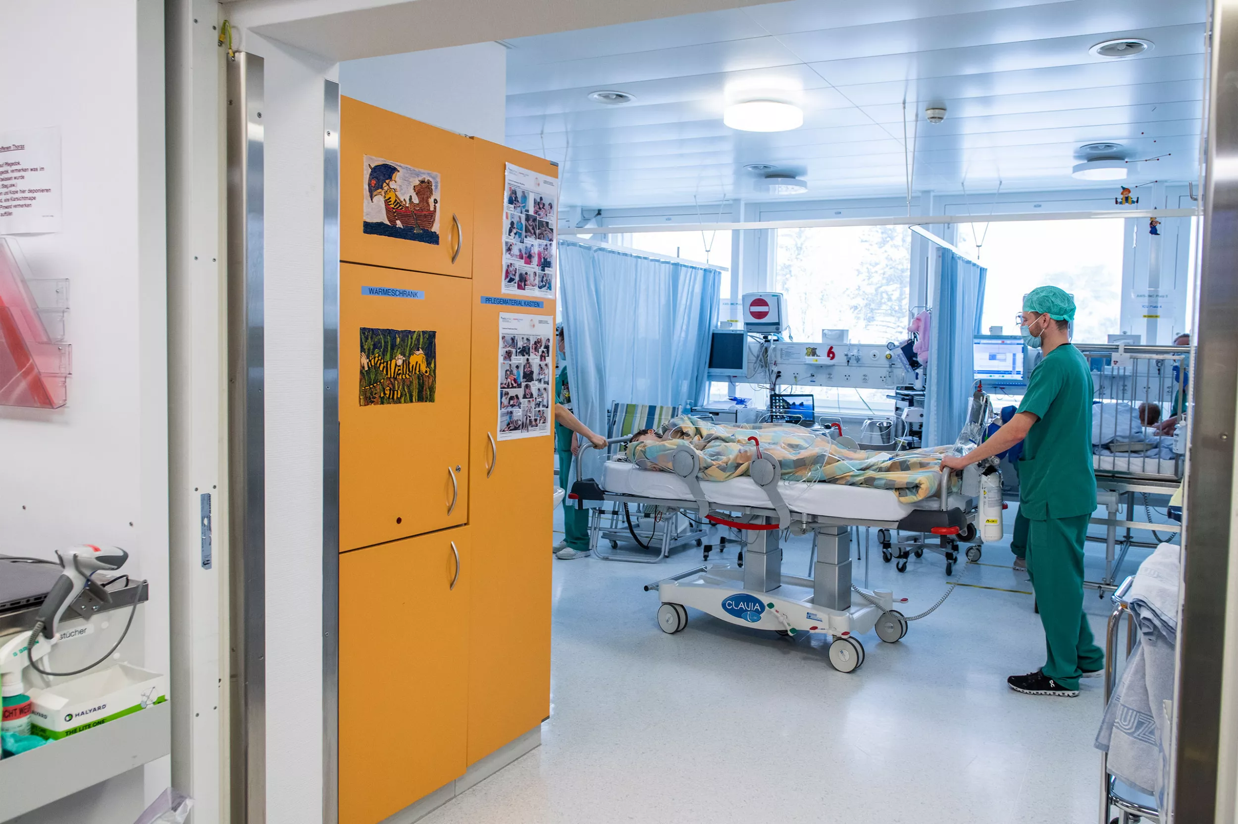 Zwei Anästhesisten bringen ein Kind im Bett nach einer Operation in die Aufwachstation