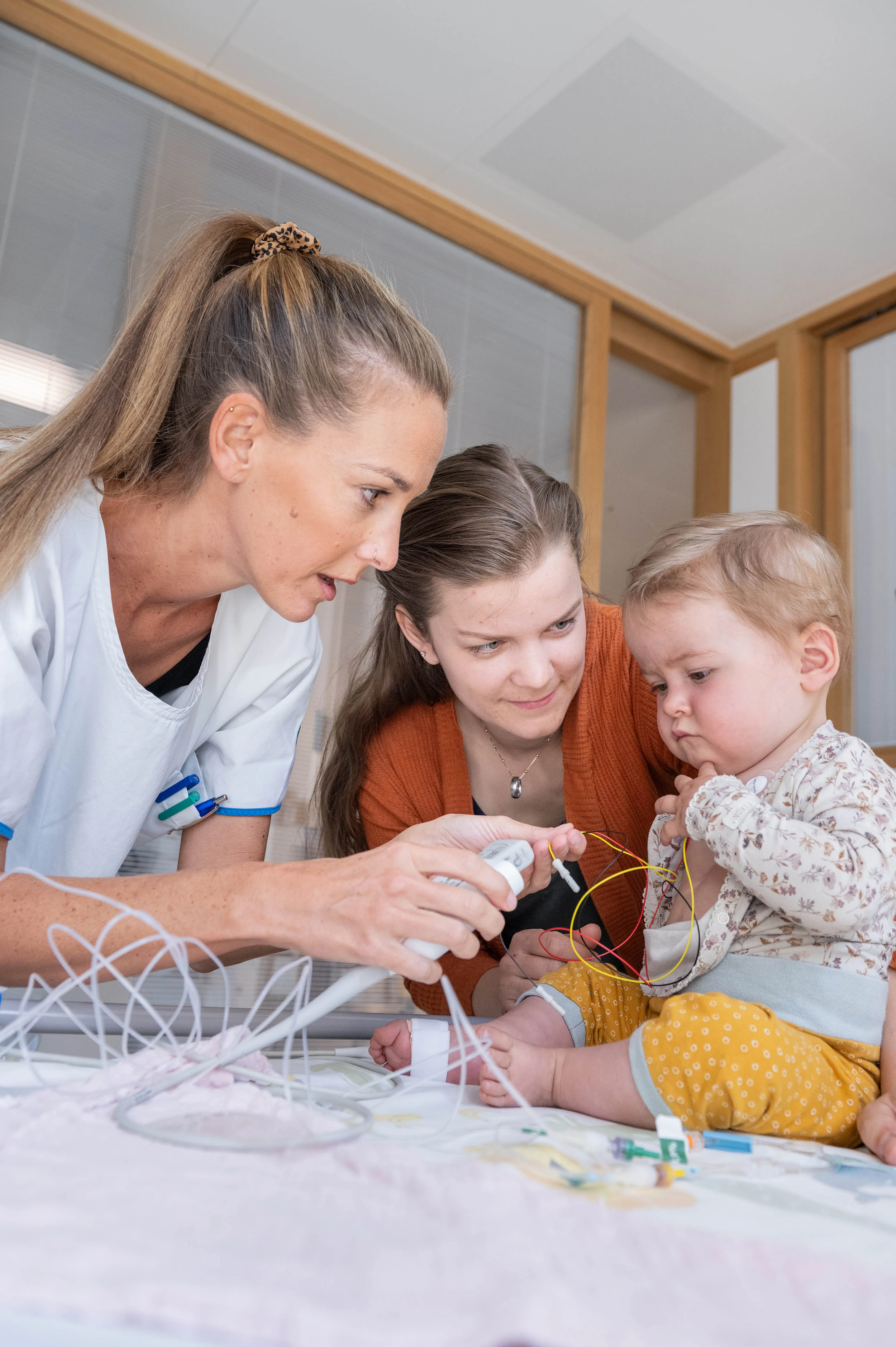 Enola sitzt im Bett und bekommt EKG Pflaster geklebt von der Pflege