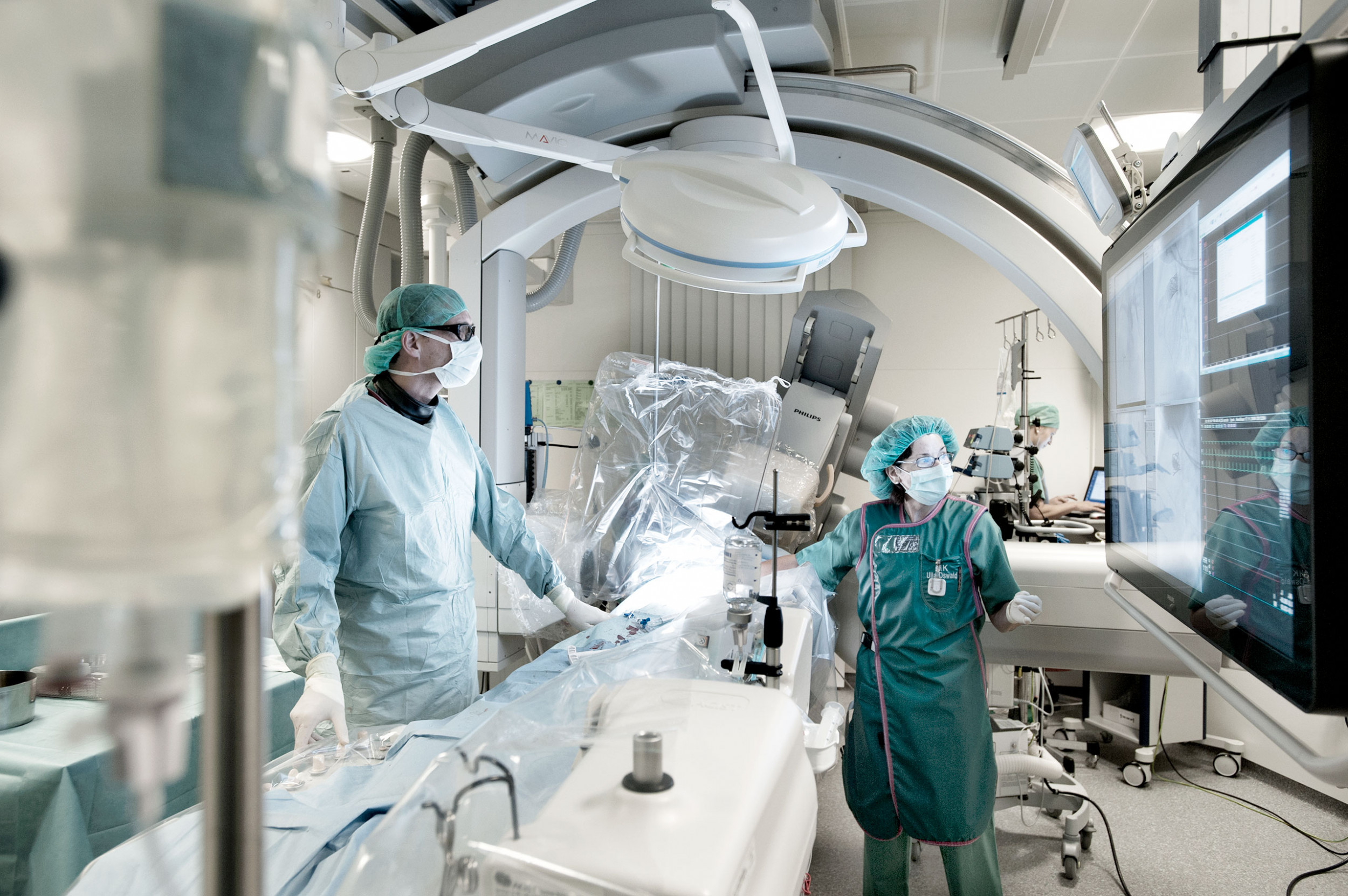 Kardiochirurg Oliver Kretschmar mit einer Pflegeexpertin schauen das Röntgenbild auf einem Bildschirm während einem Eingriff an