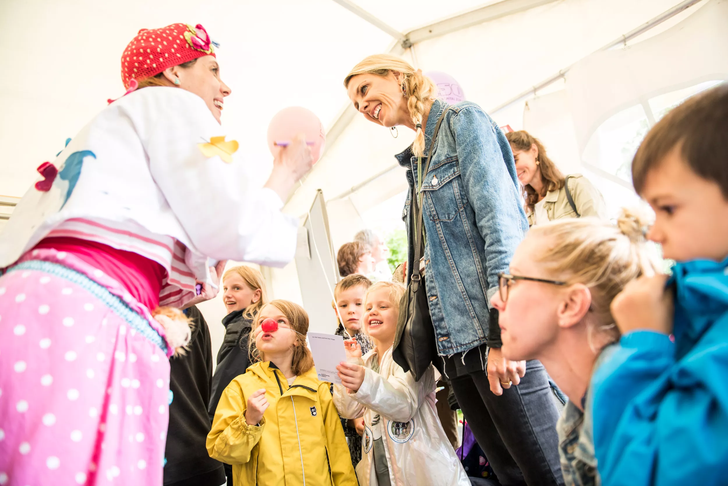 Spitalclownin umgeben von Kindern und Müttern 