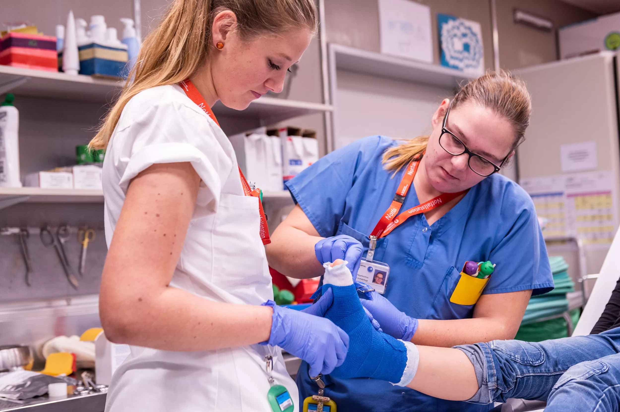 Zwei Pflegefachfrauen gipsen ein Bein