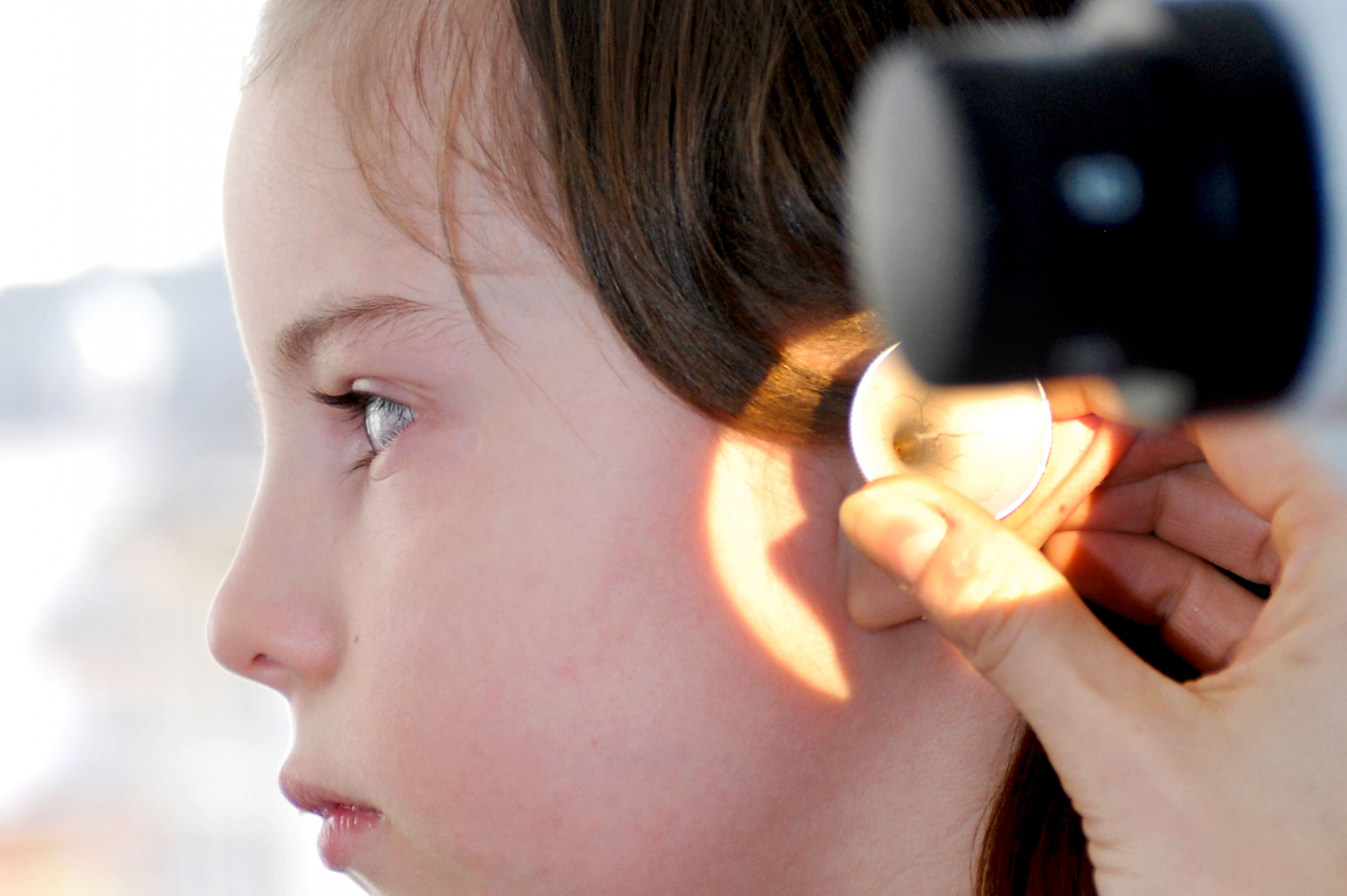 ORL-Untersuchung, Aerztin untersucht das Ohr eines Mädchen 