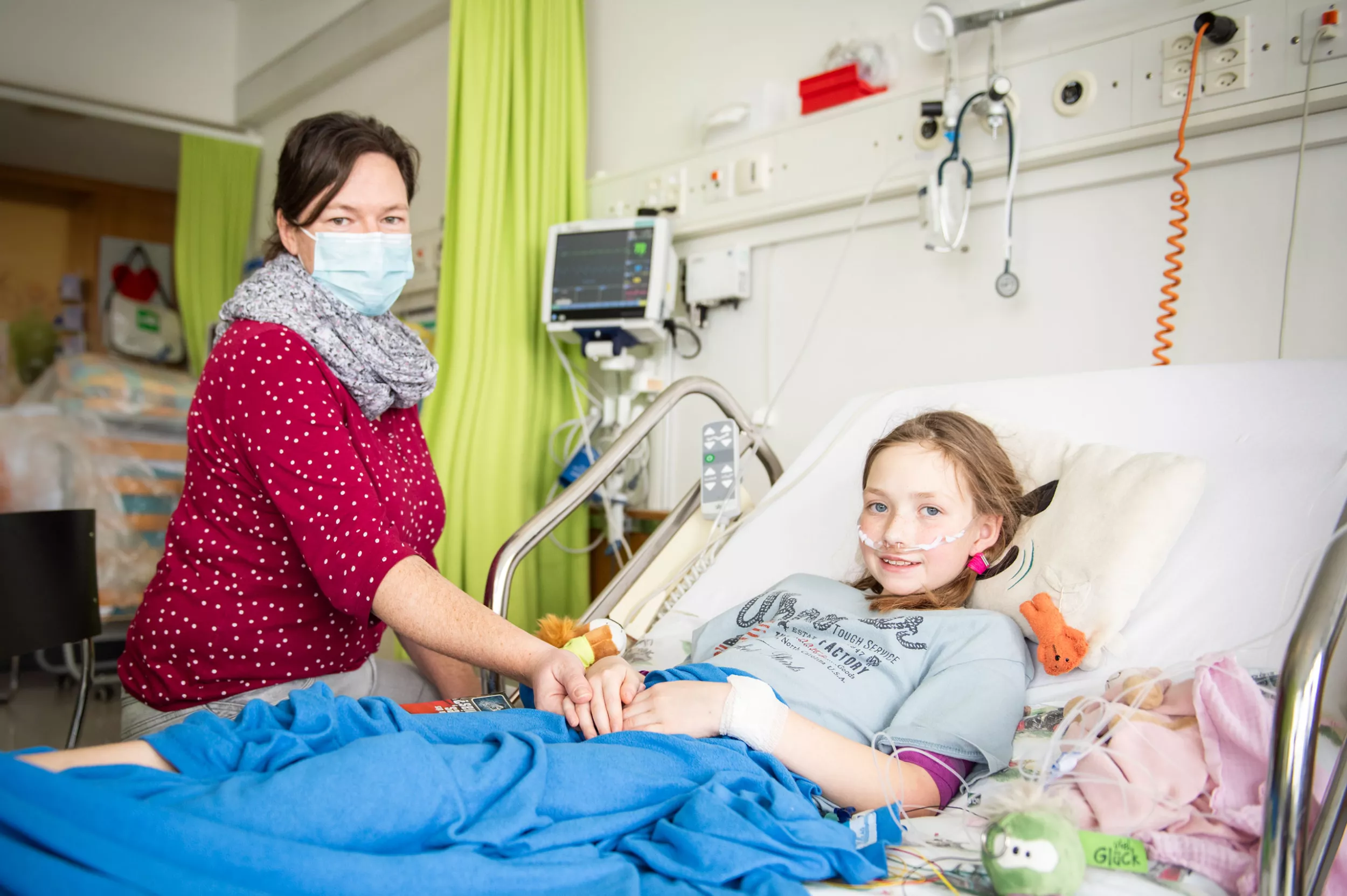 Mutter hält Hand von Tochter auf Intensivstation