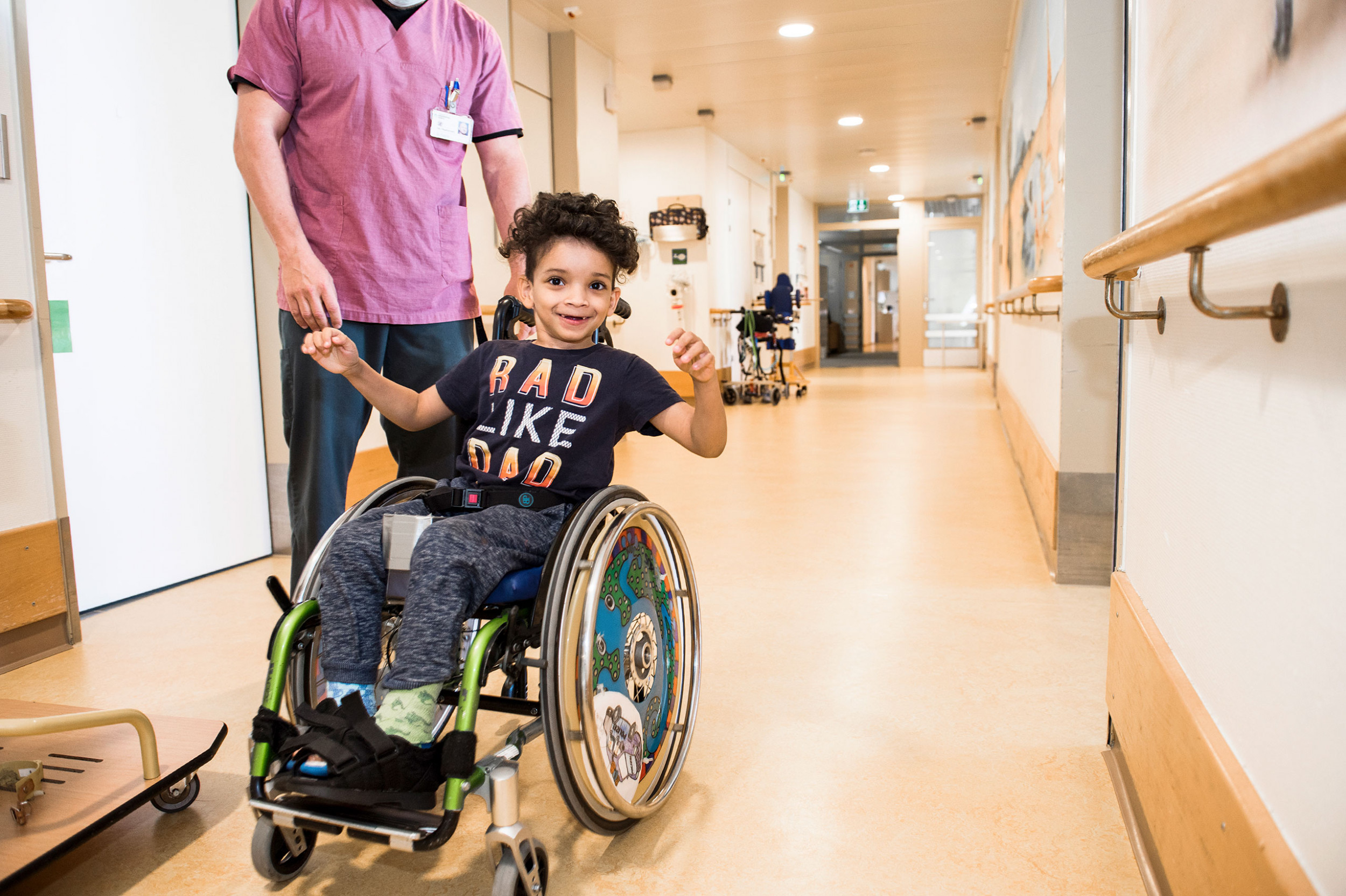 Kinder-Reha Schweiz, Patient im Rollstuhl mit Pflegefachmann im Gang
