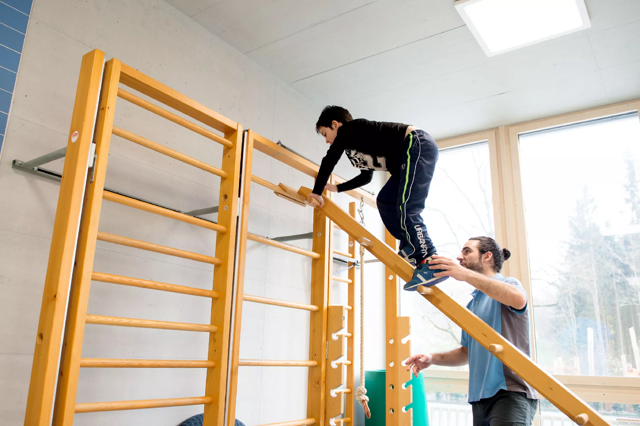 Kinder-Reha Schweiz, Physiotherapie, Therapeut mit Patient im Therapieraum beim Trainingsparcours