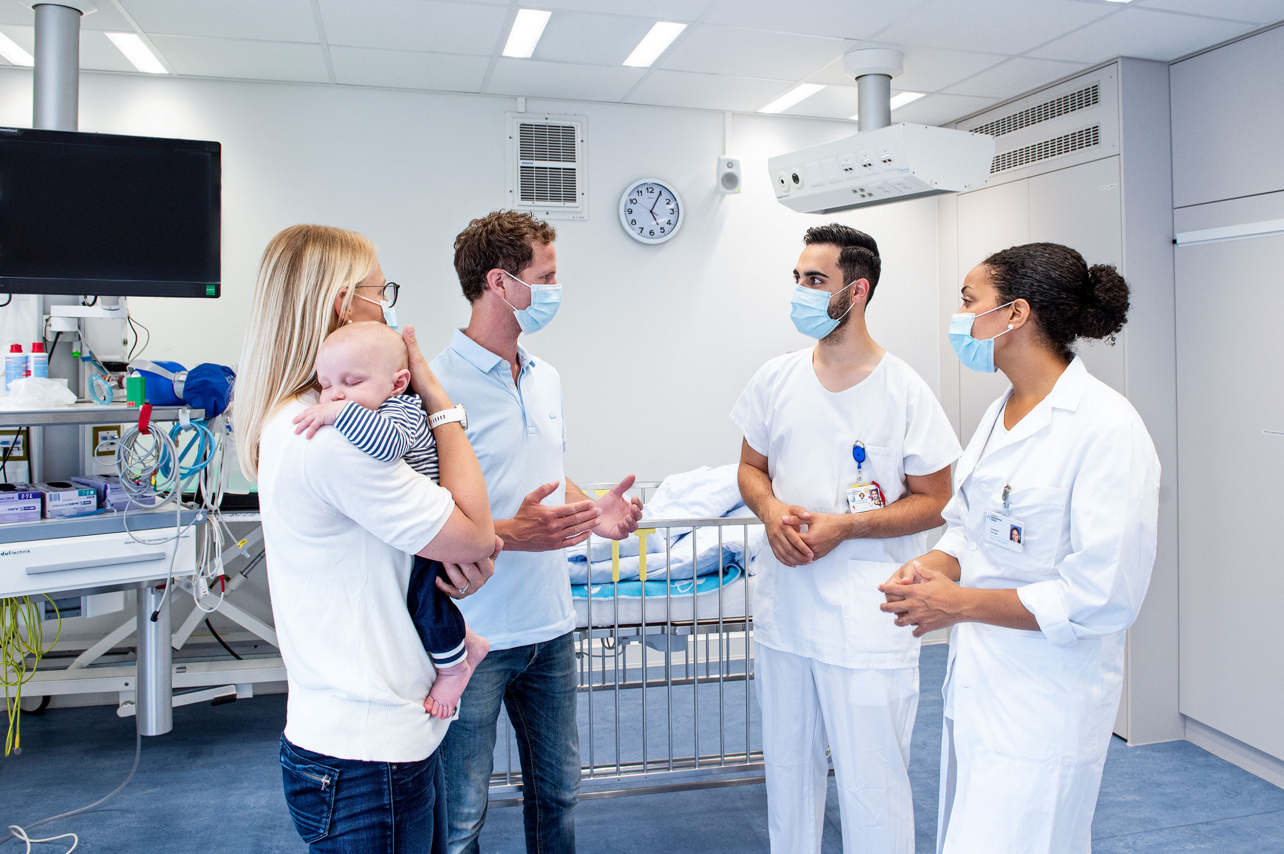 Ein Arzt, eine Ärztin und Eltern mit einem Baby reden respektvoll miteinander.