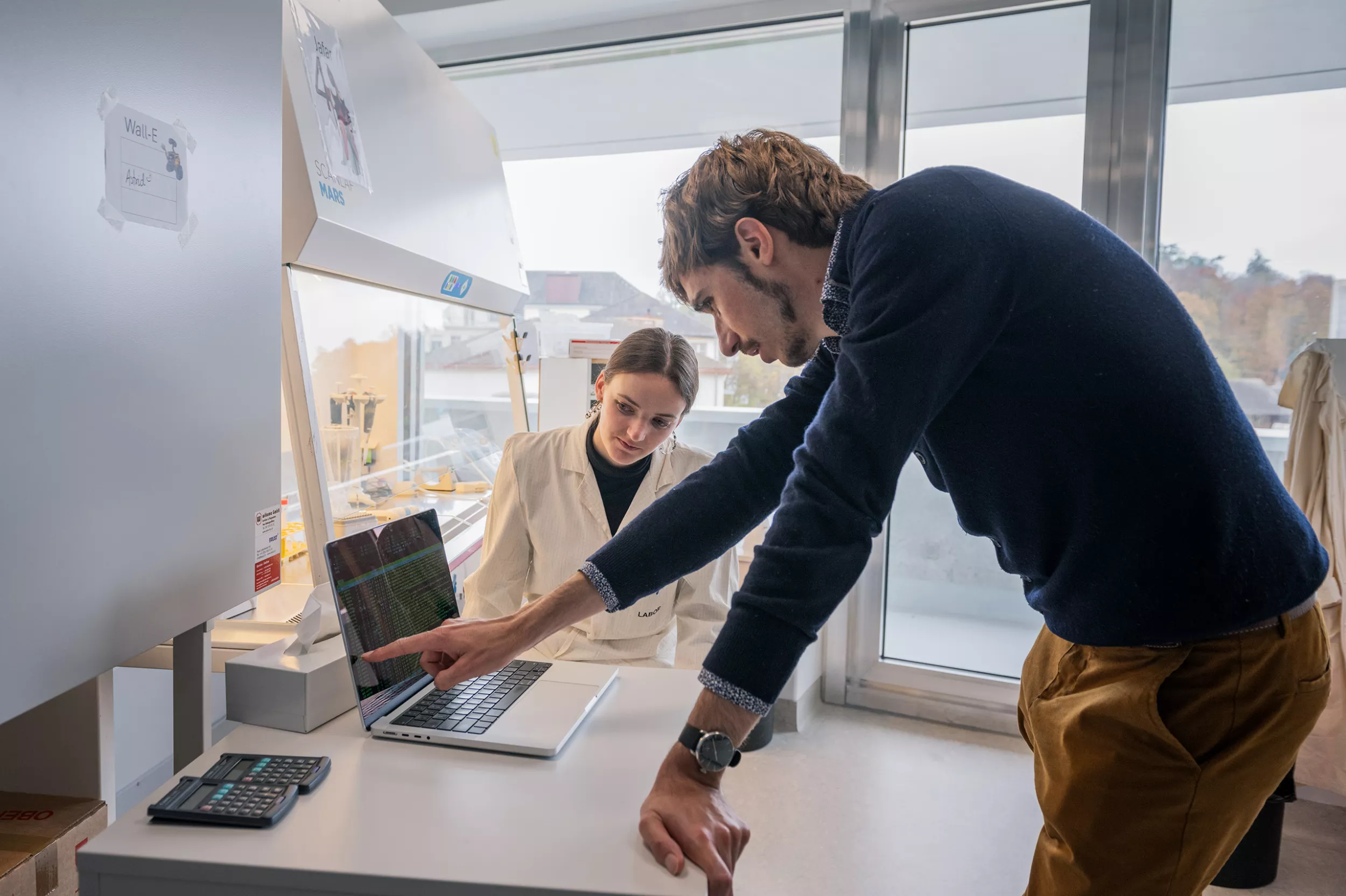 Zwei Forscher schauen sich etwas an einem Laptop im Labor