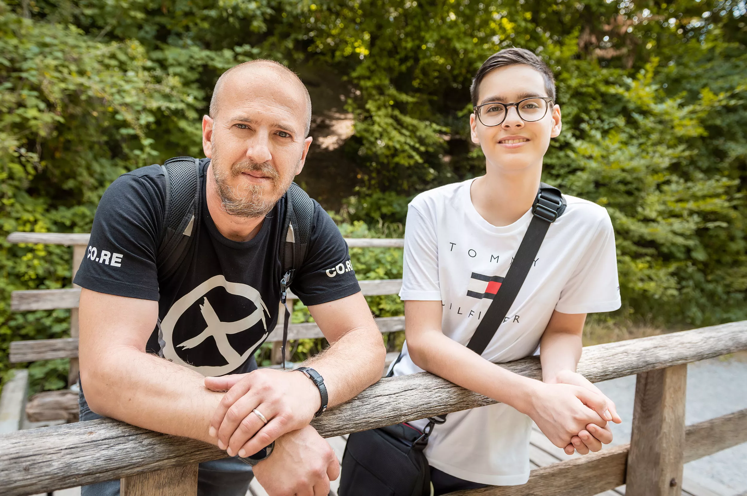 Ein Junge posiert mit seinem Vater vor der Kamera auf einer Brücke im Wald