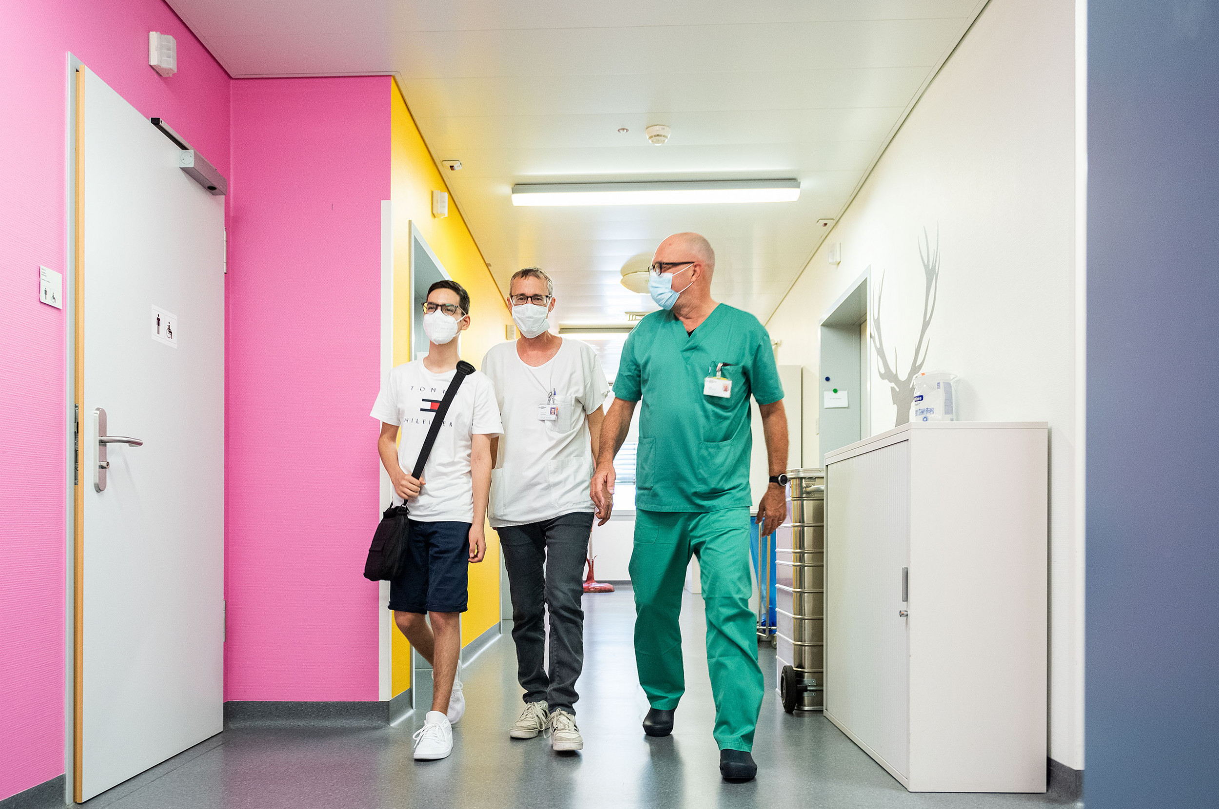 Ein Junge läuft zusammen mit einem Kardiotechniker und einem Herzchirurg im Kinderspital Zürich