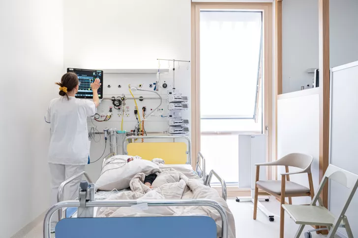 Eine Pflegefachfrau überwacht die Werte eines Patienten im Aufwachraum nach einer Operation