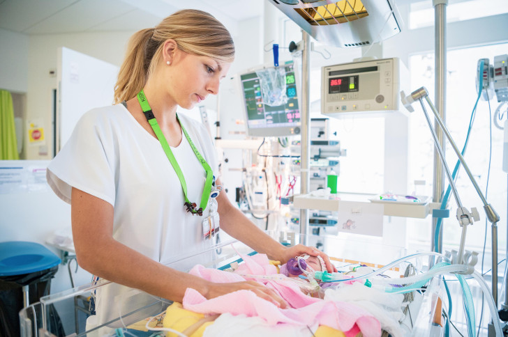 Pflegefachperson mit Neugeborenem auf der Intensivstation
