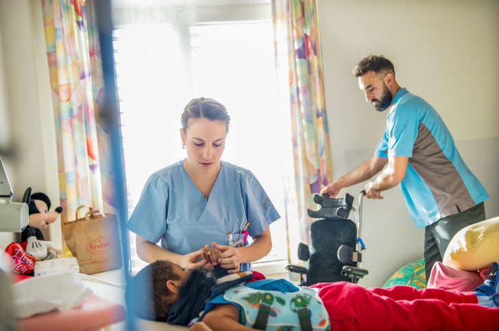 Kinder-Reha Schweiz, Pflegefachfrau zieht ein Kind im Bett an