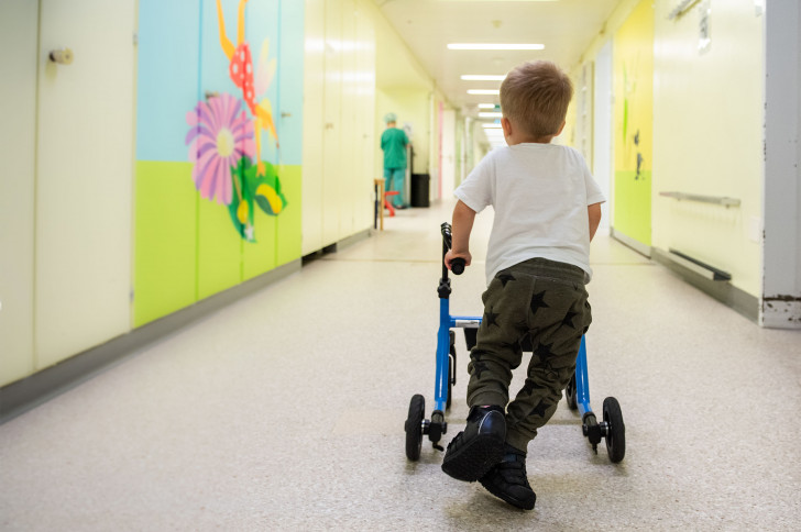 Ein Junge läuft mit seinem Rollator durch den gang des Kinderspitals