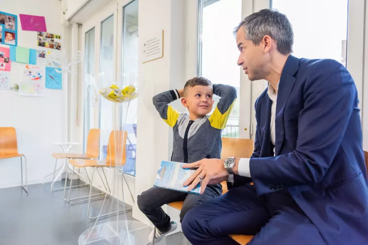 Ein Vater mit einem Kind unterhalten sich im Wartebereich im Kinderspital Zürich